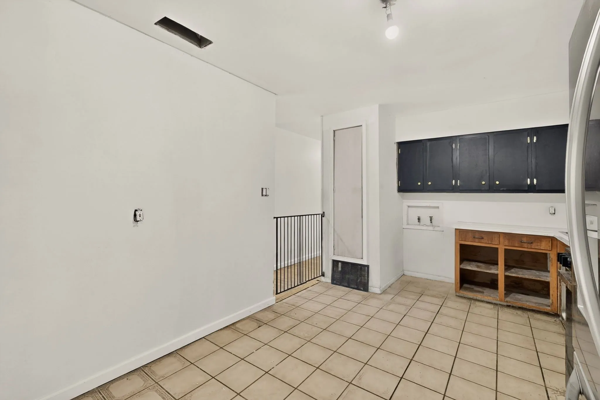 Tile flooring, black upper cabinetry, and partial wood-finish lower cabinetry