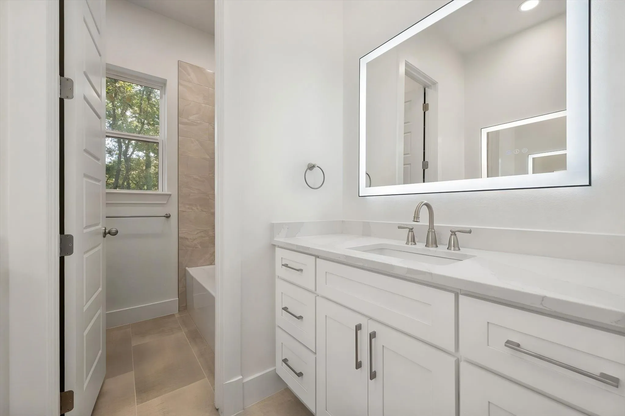 Guest bathroom overview showcasing sleek quartz counters, brushed nickel hardware, and neutral tile flooring.