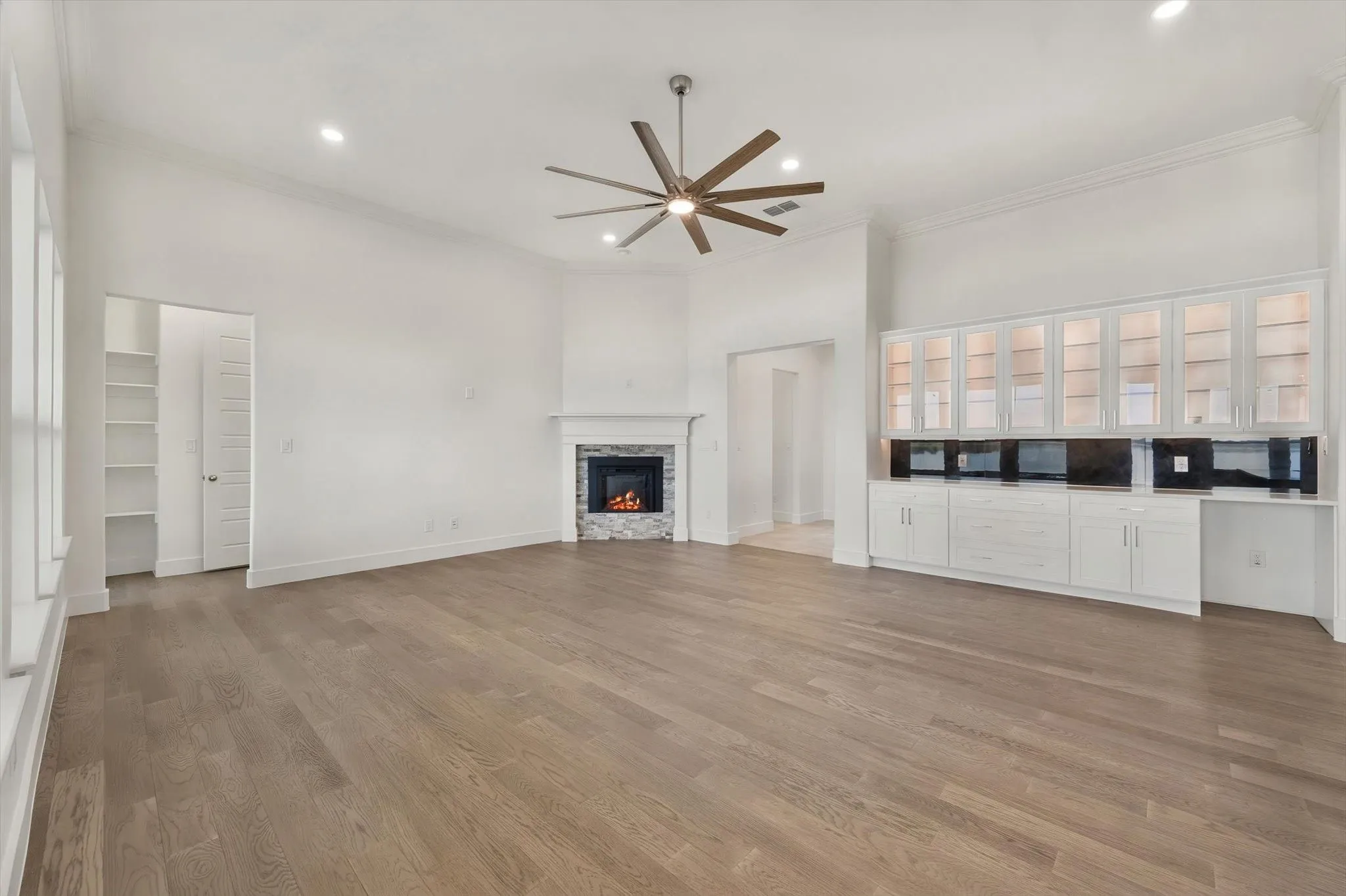 Cozy living space anchored by a stone-surround corner fireplace and illuminated glass-door display cabinets.