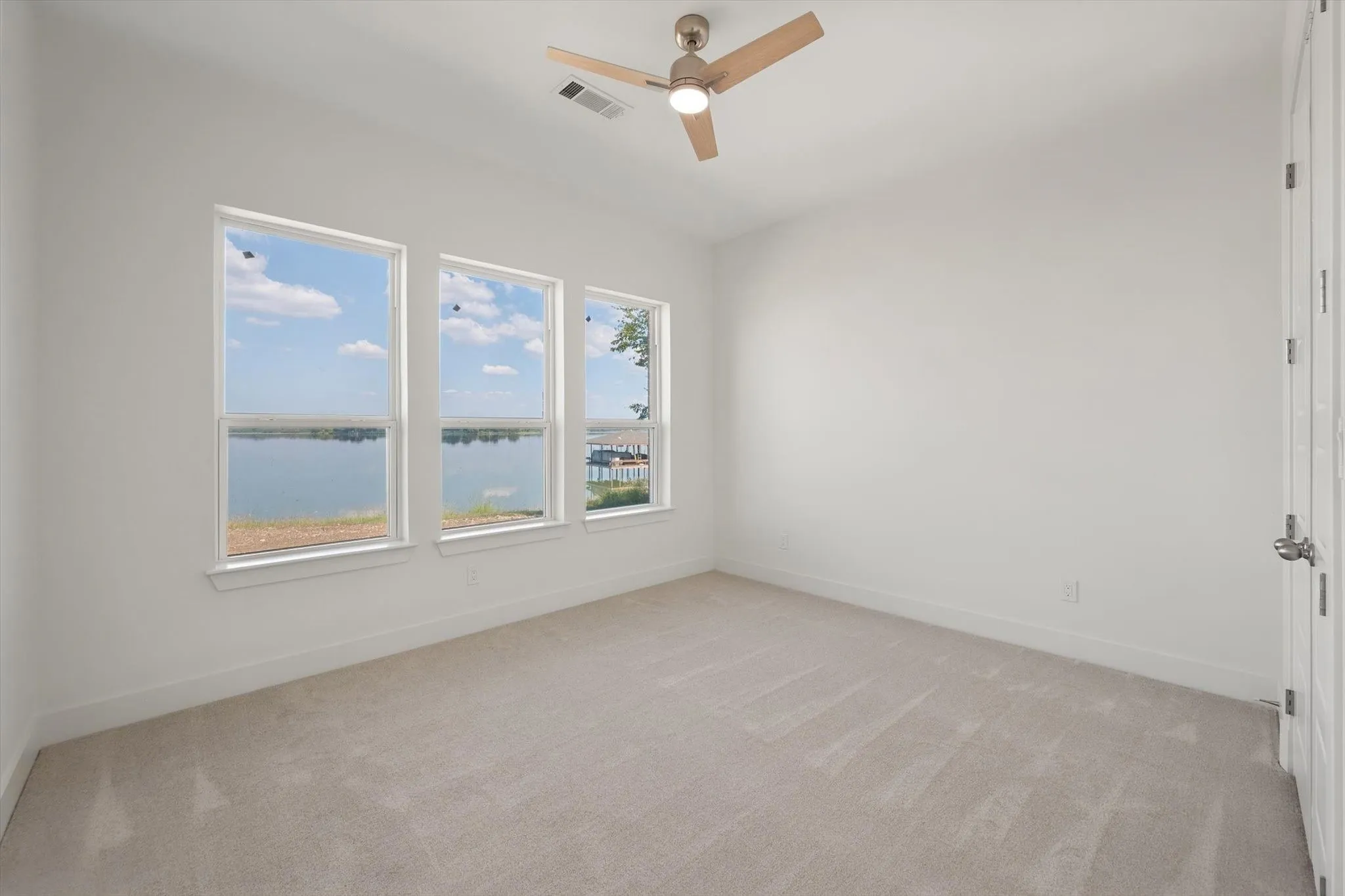 Peaceful bedroom in this Corsicana, TX home featuring a triple-window wall directly overlooking the lake and nearby docks.