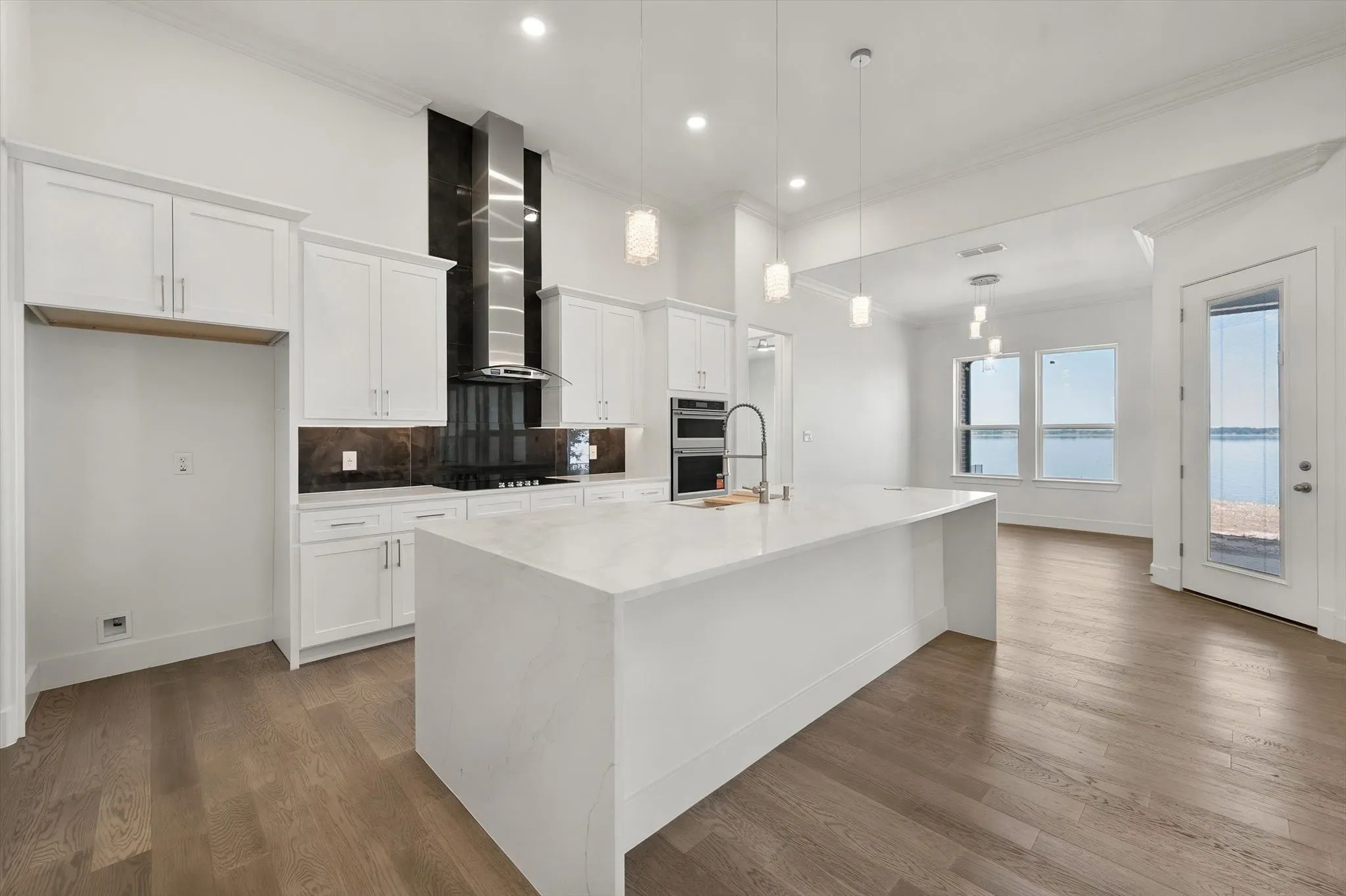 Light-filled kitchen space connecting seamlessly to a breakfast nook overlooking serene water views.