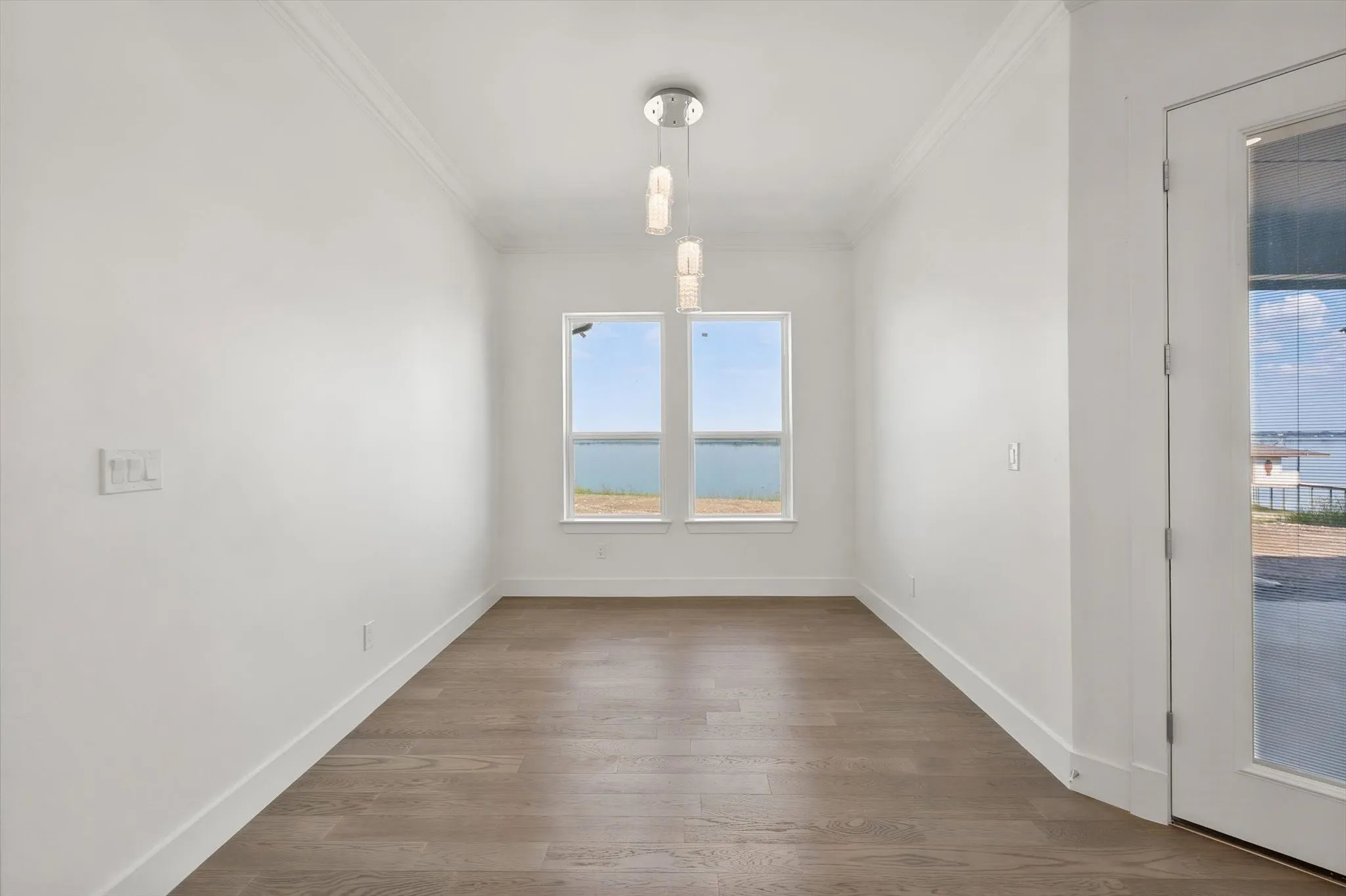 Dedicated dining alcove featuring elegant multi-pendant lighting and large windows framing panoramic Richland Chambers Lake vistas.
