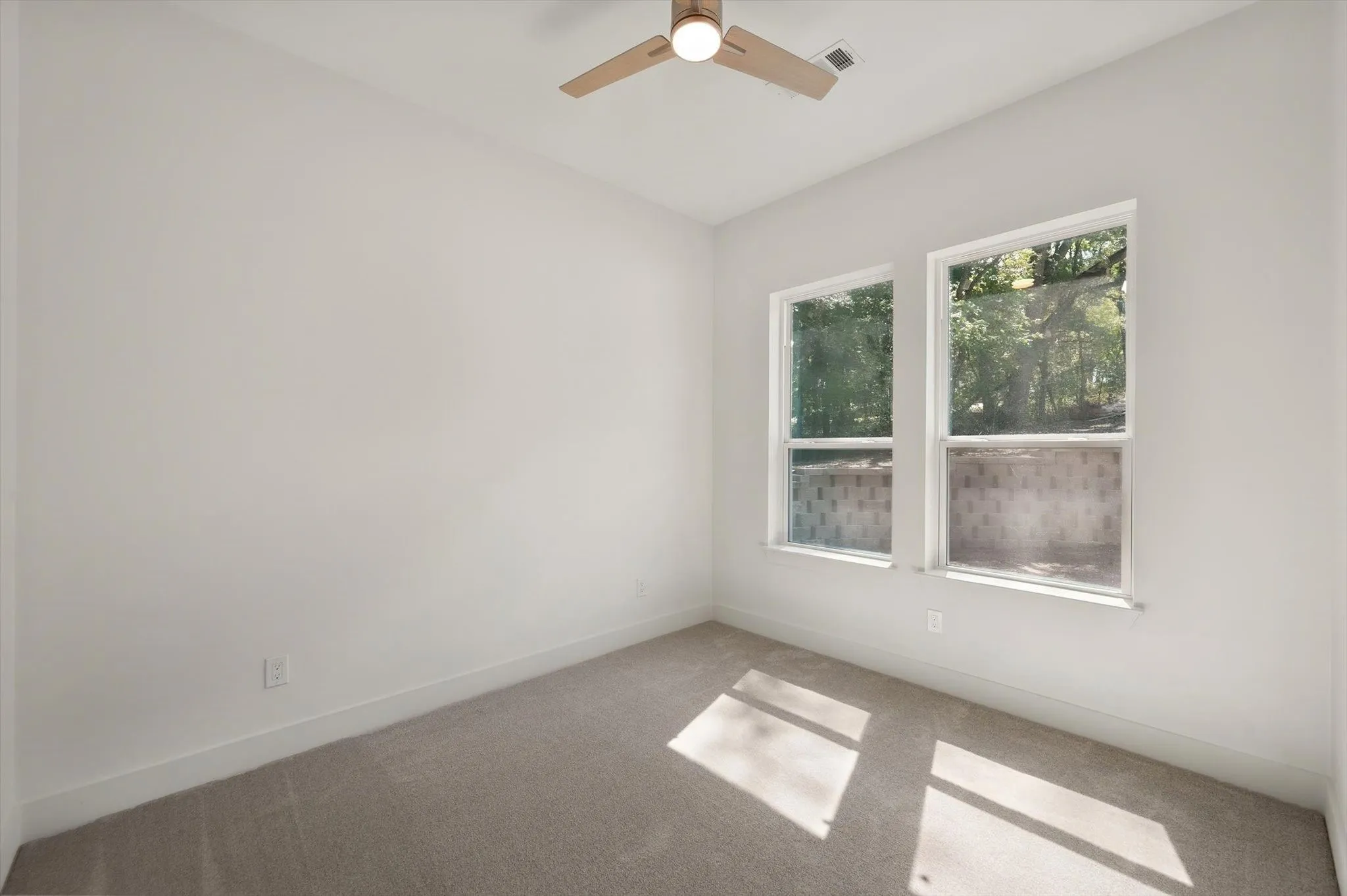 Cozy secondary bedroom offering neutral wall tones, plush carpeting, ceiling fan, and ample natural light.