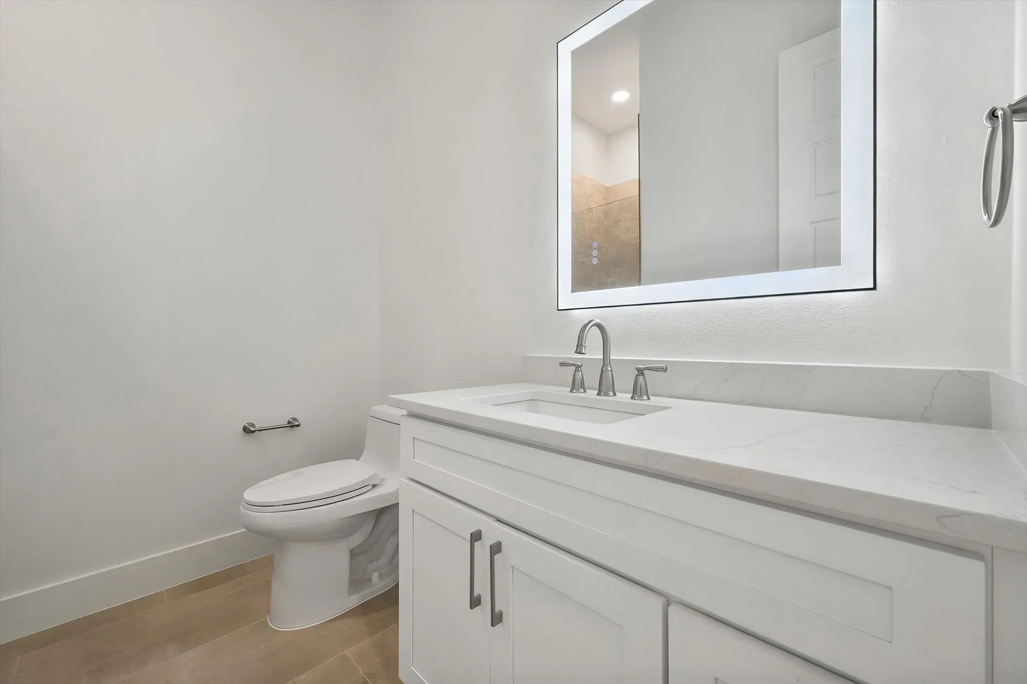 Stylish guest bathroom featuring an LED halo-lit mirror, quartz countertop vanity, and brushed nickel fixtures.