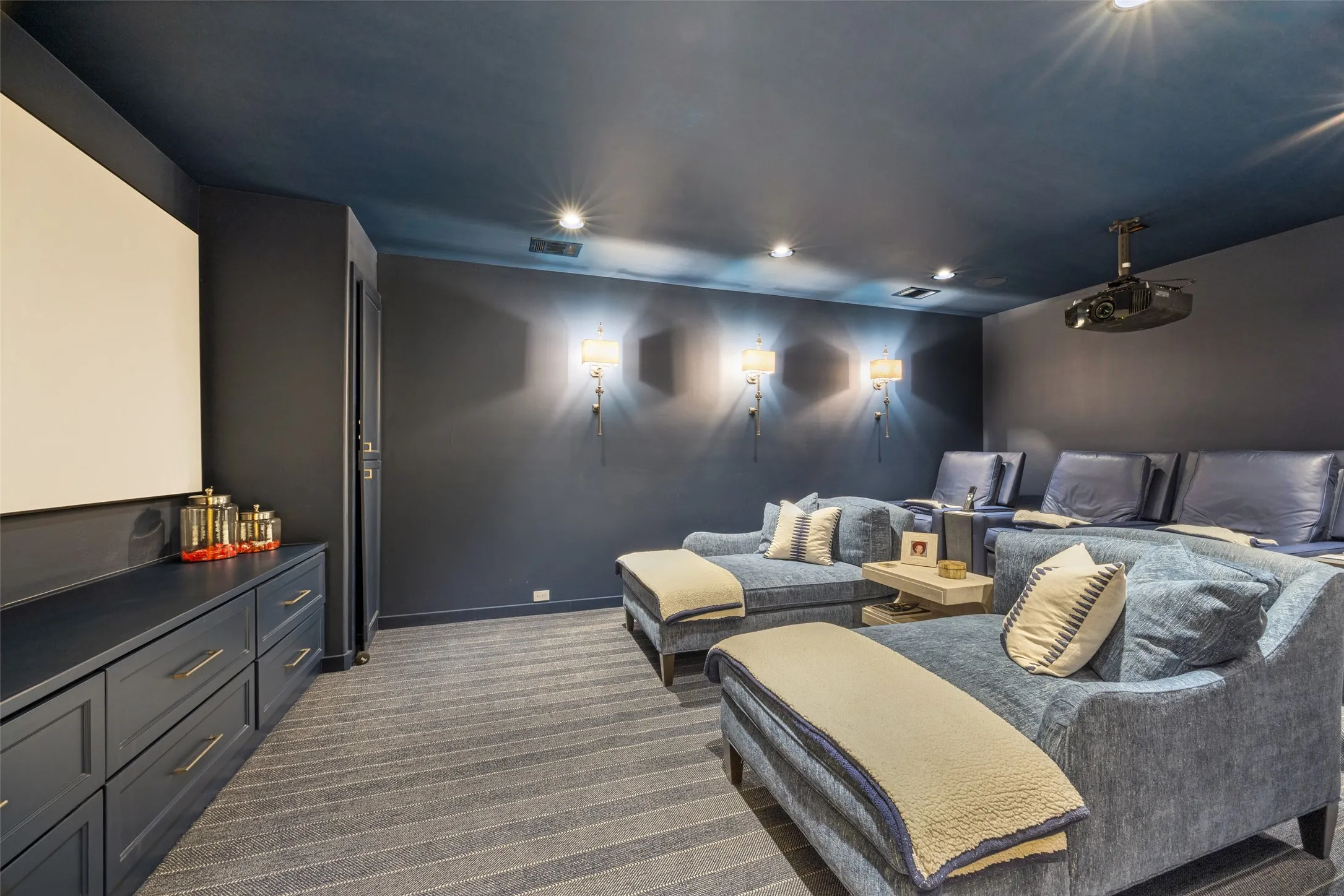 Media room featuring a projector, recessed lighting, and wall sconces