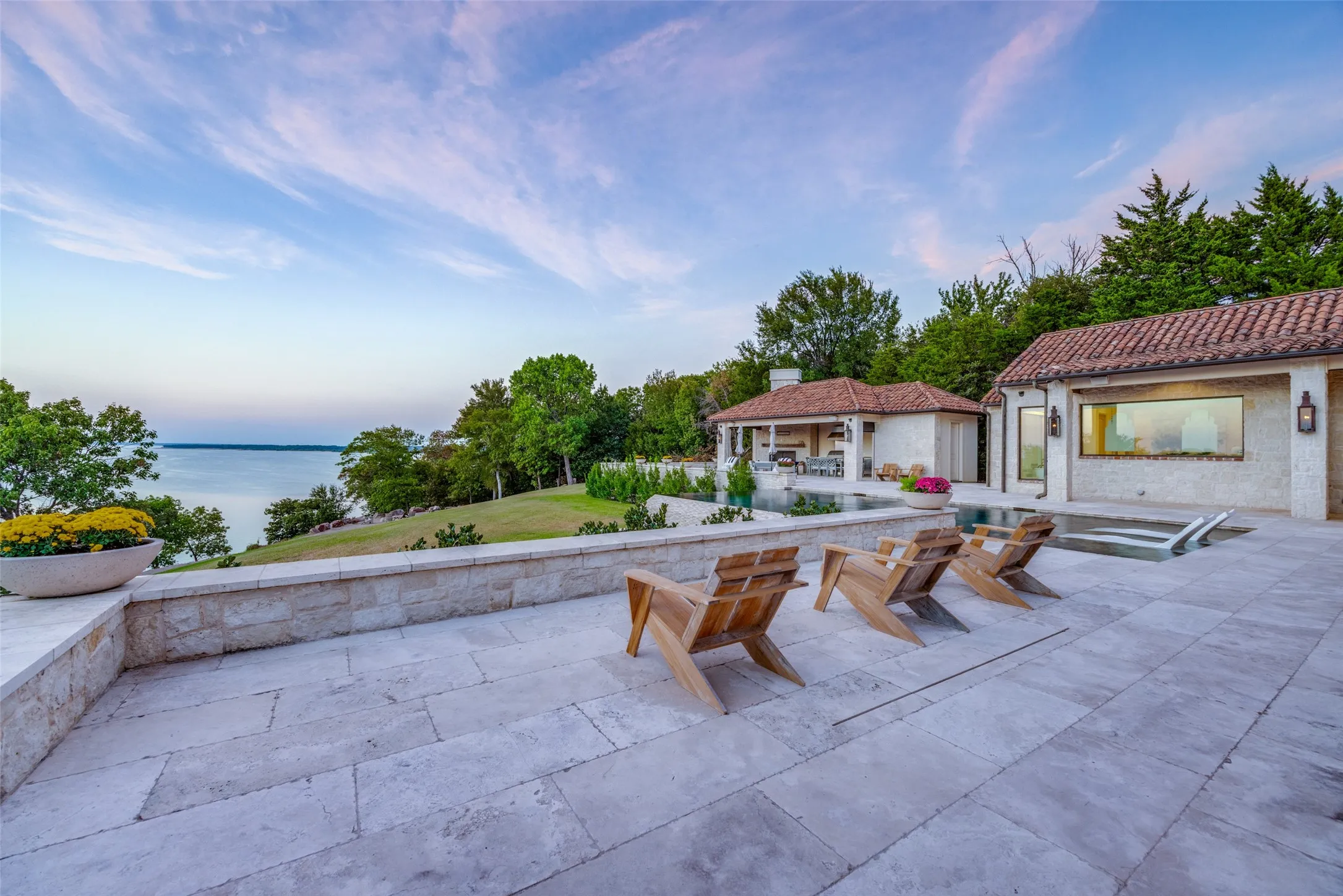Expansive stone patio with a retaining wall, overlooking a body of water