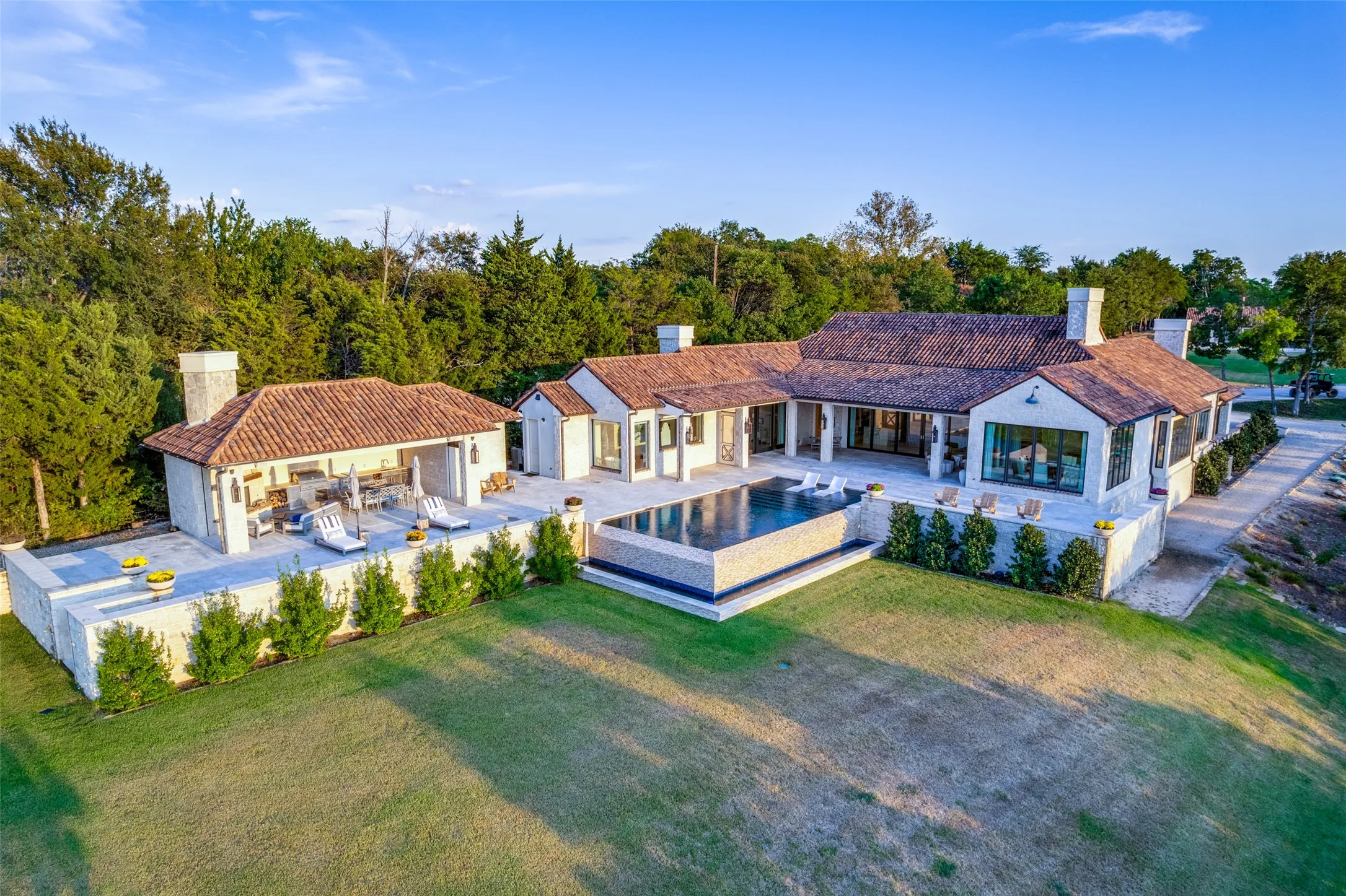 Spanish Colonial-inspired exterior with terracotta roof tiles, white stucco walls, and an infinity-edge pool