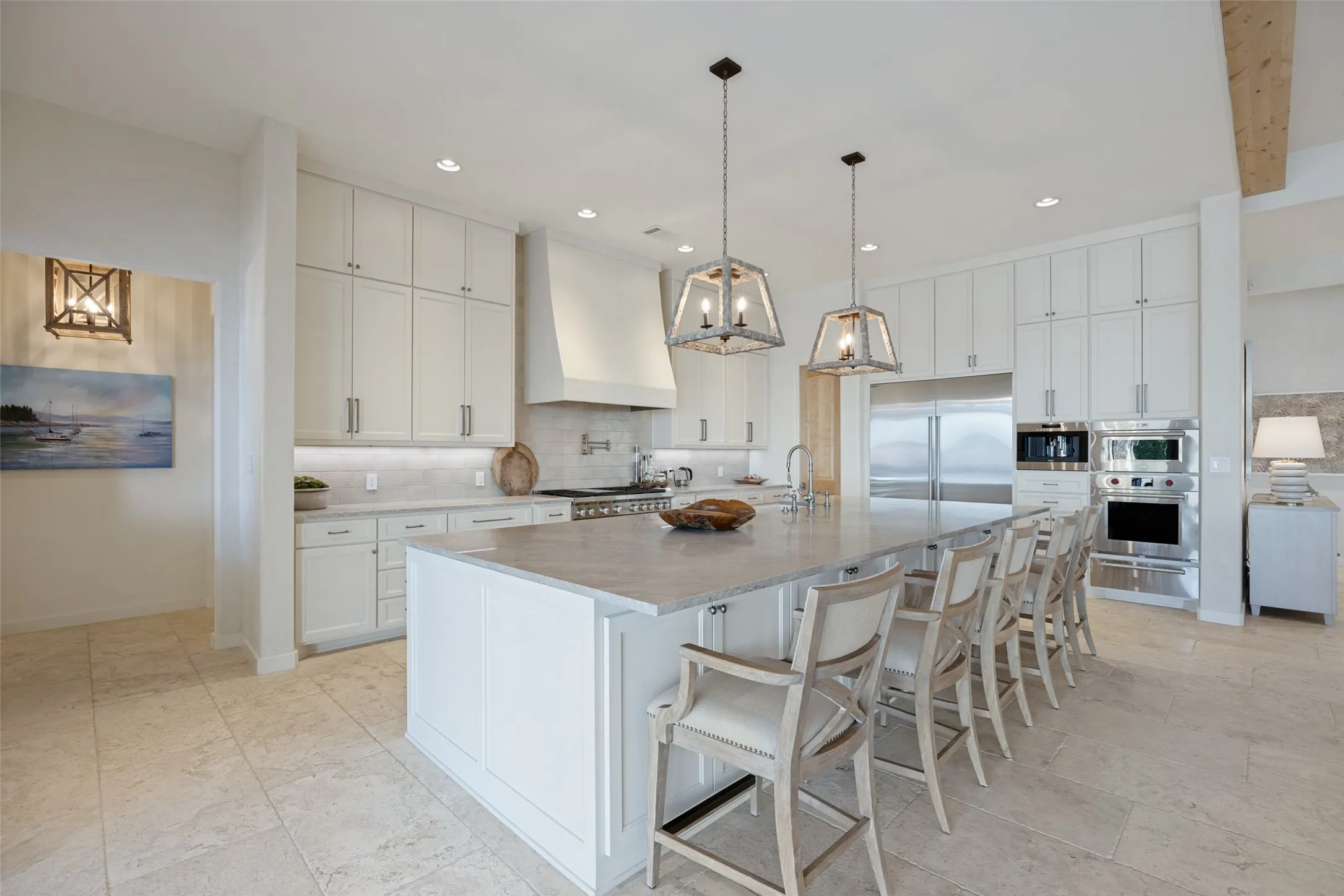 Spacious kitchen featuring an expansive center island, white cabinetry, stainless steel appliances, pendant lighting, and tiled flooring