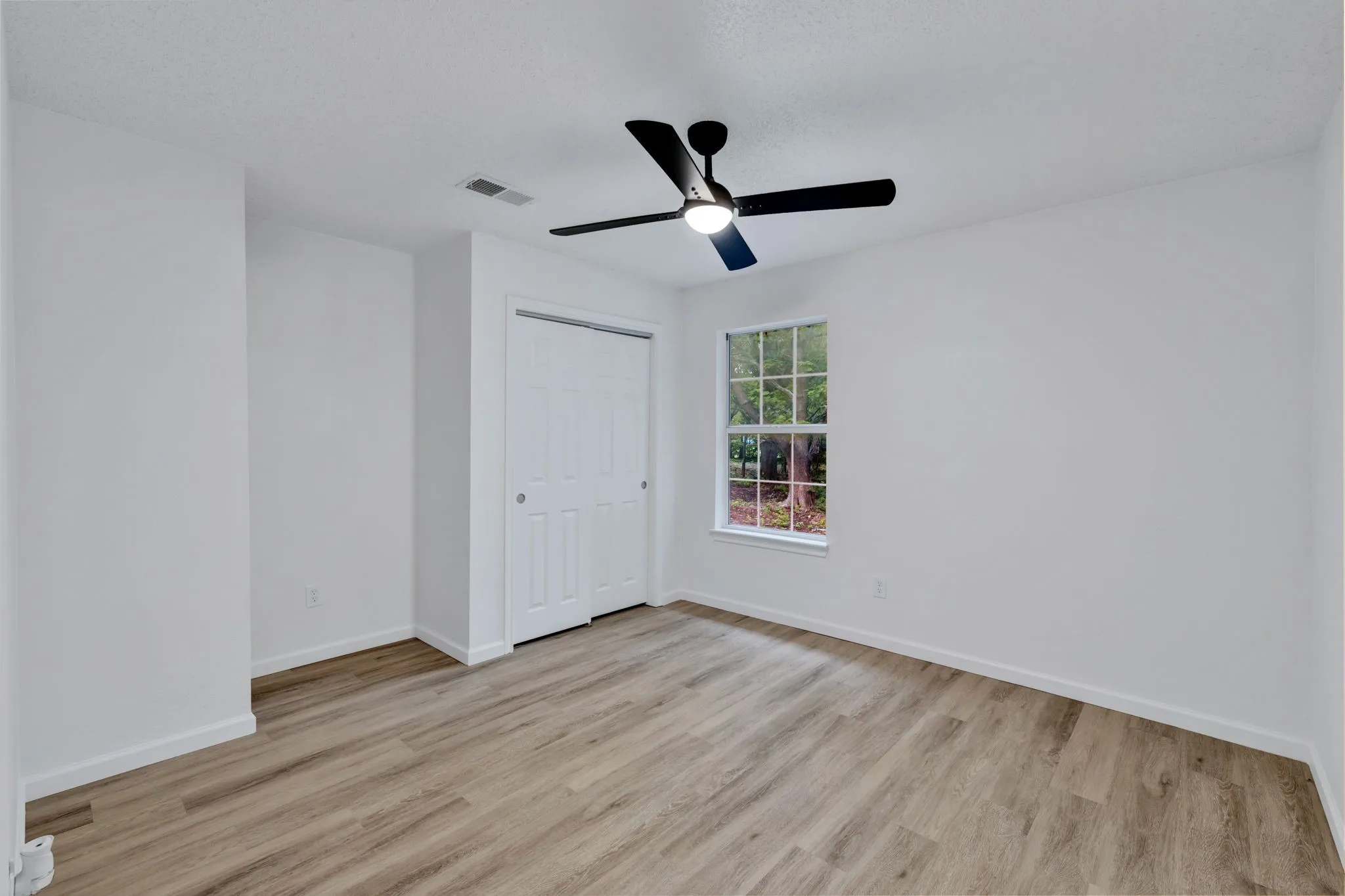 Wood-finish flooring, white walls, and a window with exterior visibility