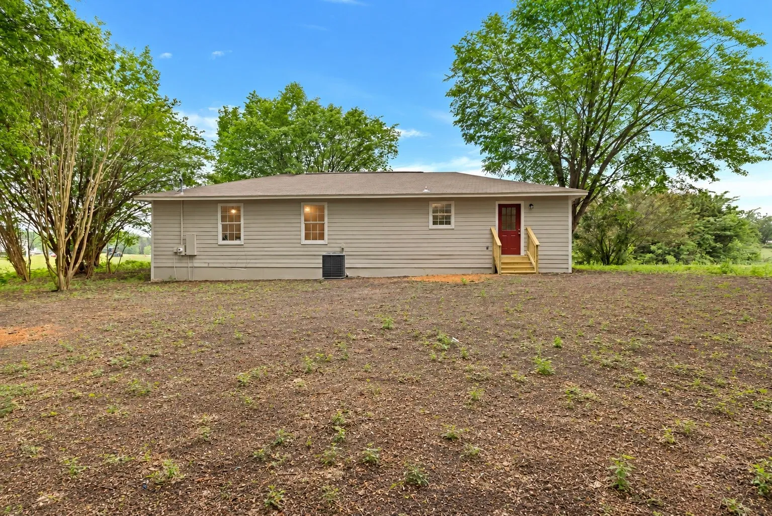 Charming single-story residence featuring horizontal vinyl siding, a welcoming red entry door with yellow trim, and multiple windows providing natural light