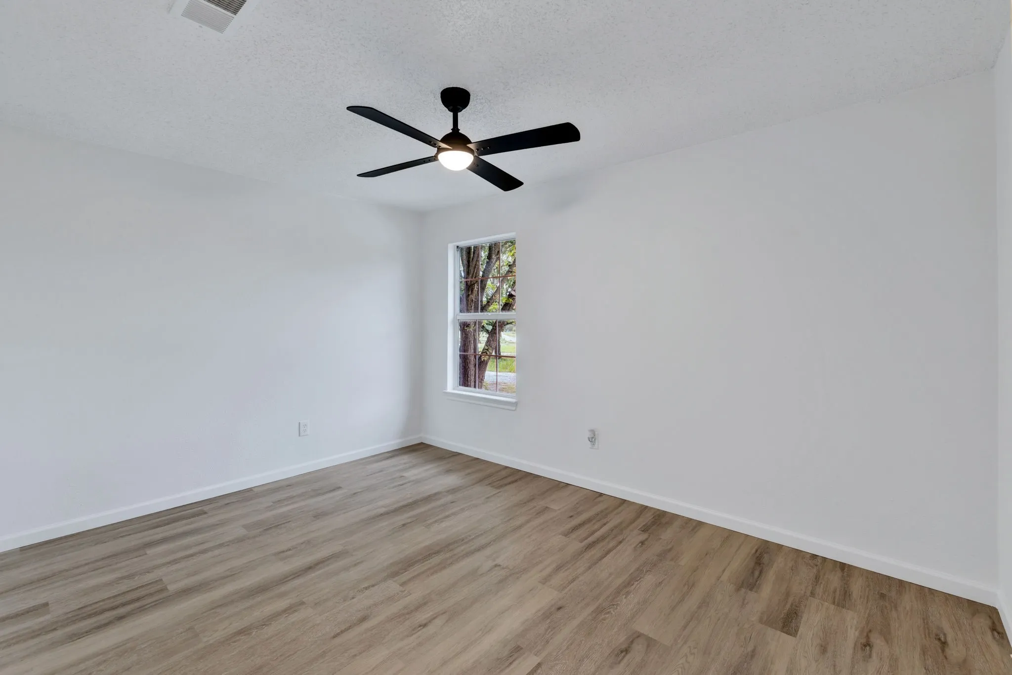 Recessed window with white trim, wood-finish flooring, and a ceiling fan with integrated lighting