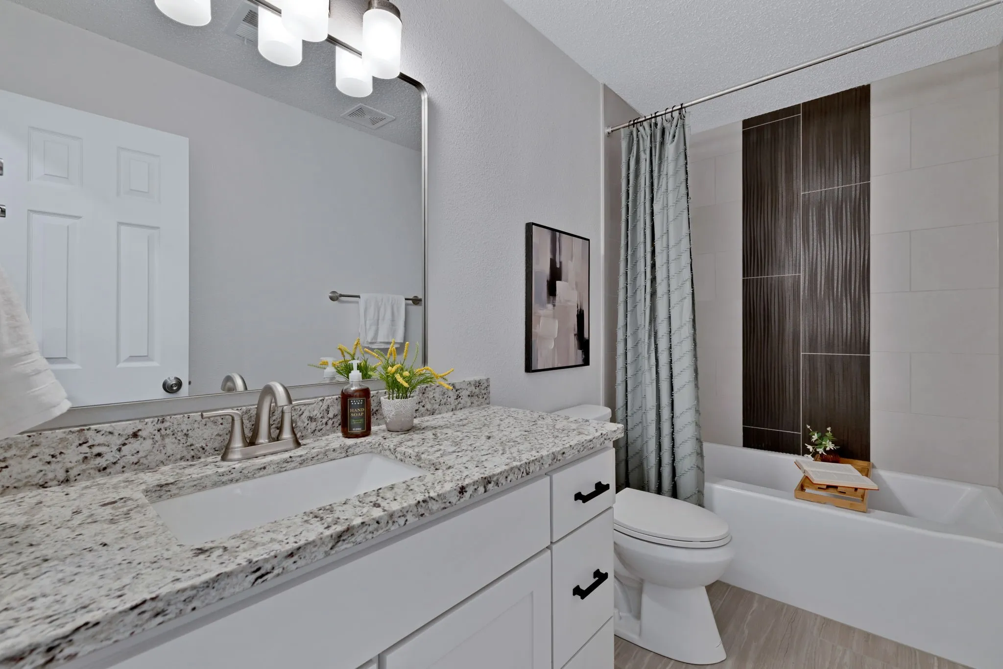 White shaker-style vanity with granite countertop, undermount sink, and brushed nickel faucet