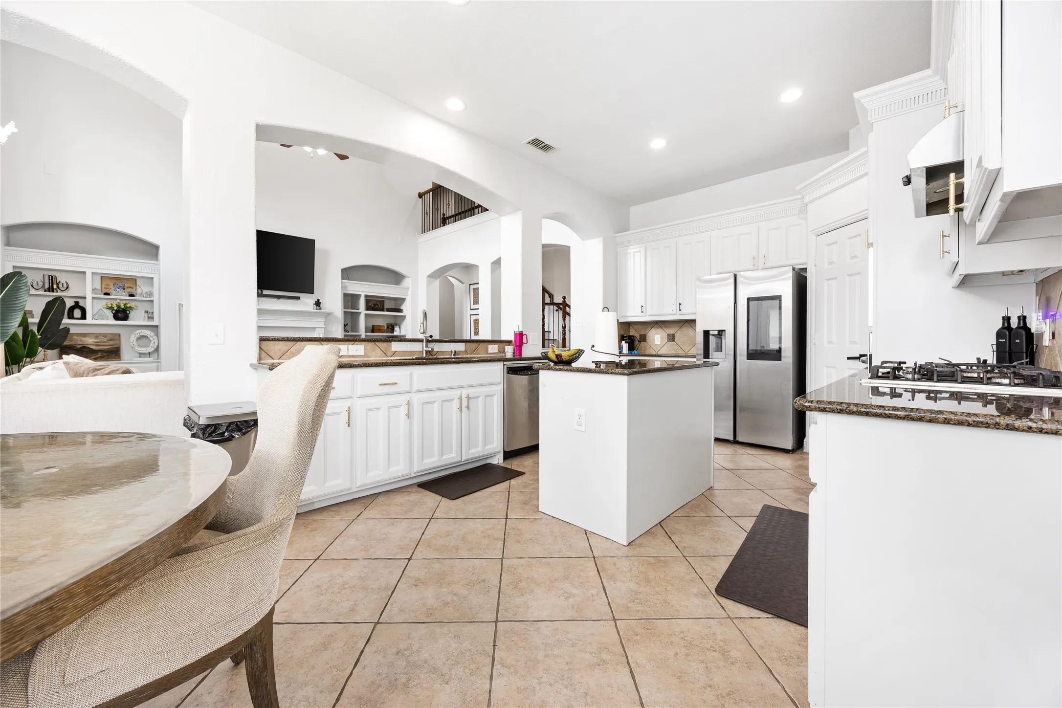 Kitchen featuring white cabinetry, a central island, stainless steel appliances, granite countertops, and tile flooring
