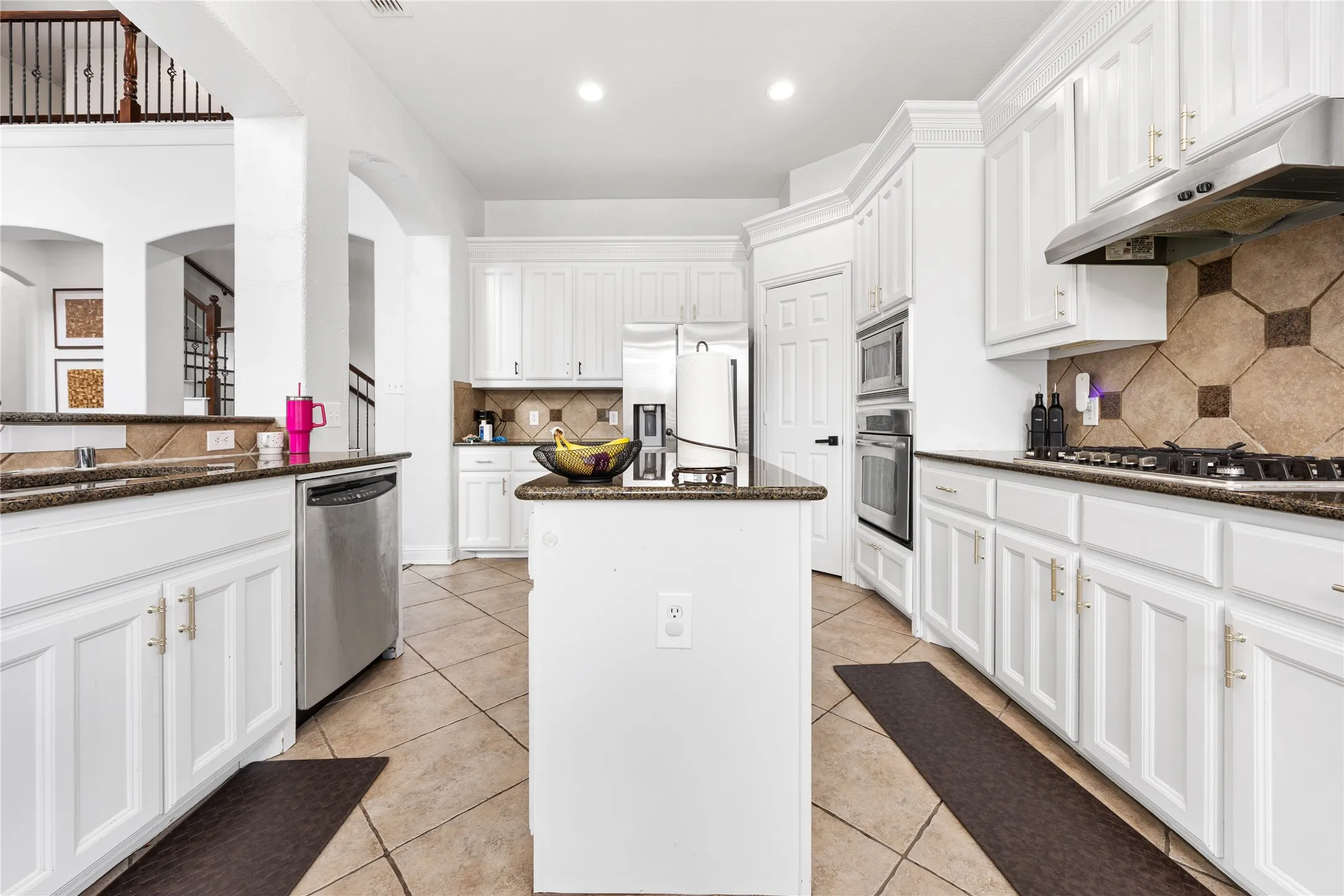 Kitchen featuring white cabinetry, dark stone countertops, stainless steel appliances, and a tiled backsplash