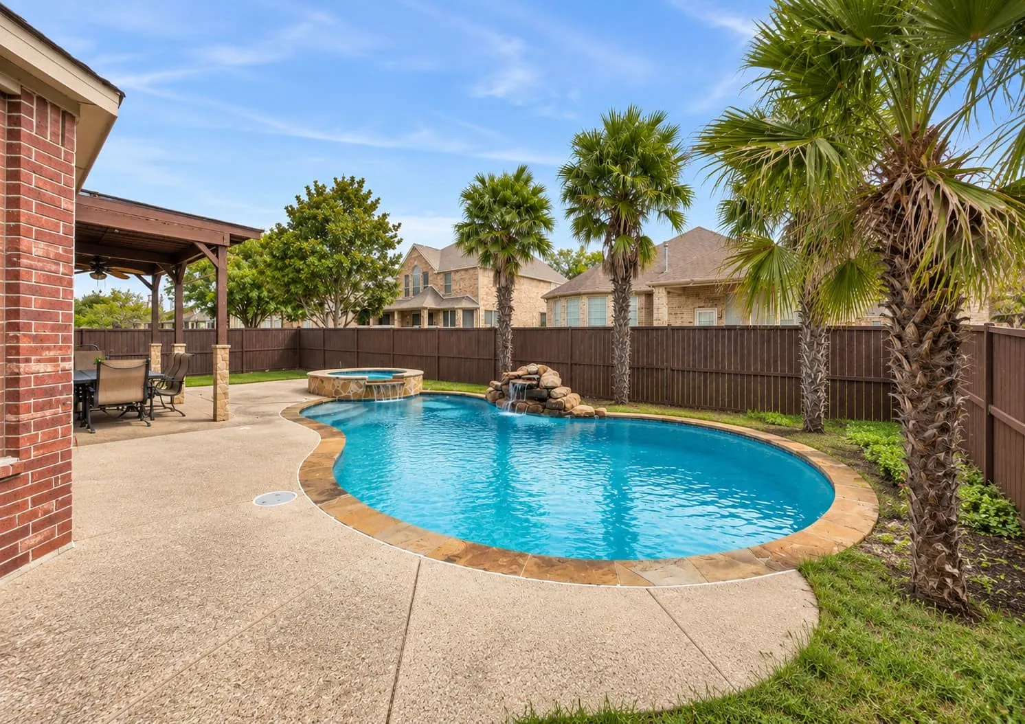 Outdoor living area featuring a custom-shaped pool with integrated spa and rock waterfall