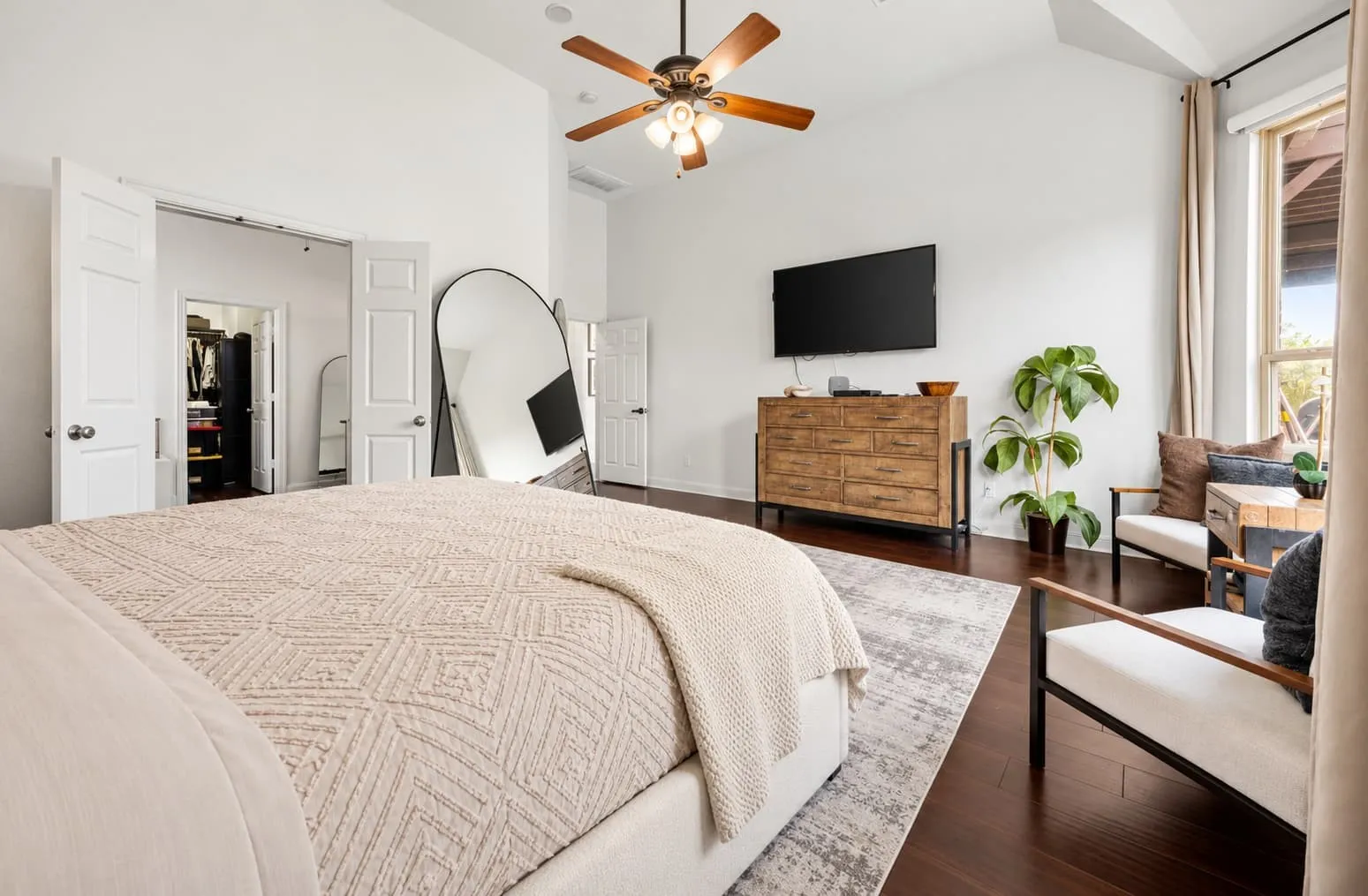 Vaulted ceiling with a ceiling fan, dark wood-finish flooring, and large windows