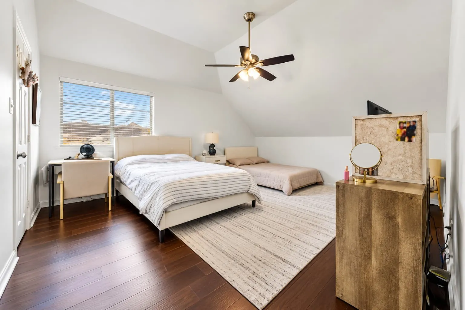 Angled ceiling lines, dark wood-finish flooring, and a ceiling fan with integrated lighting