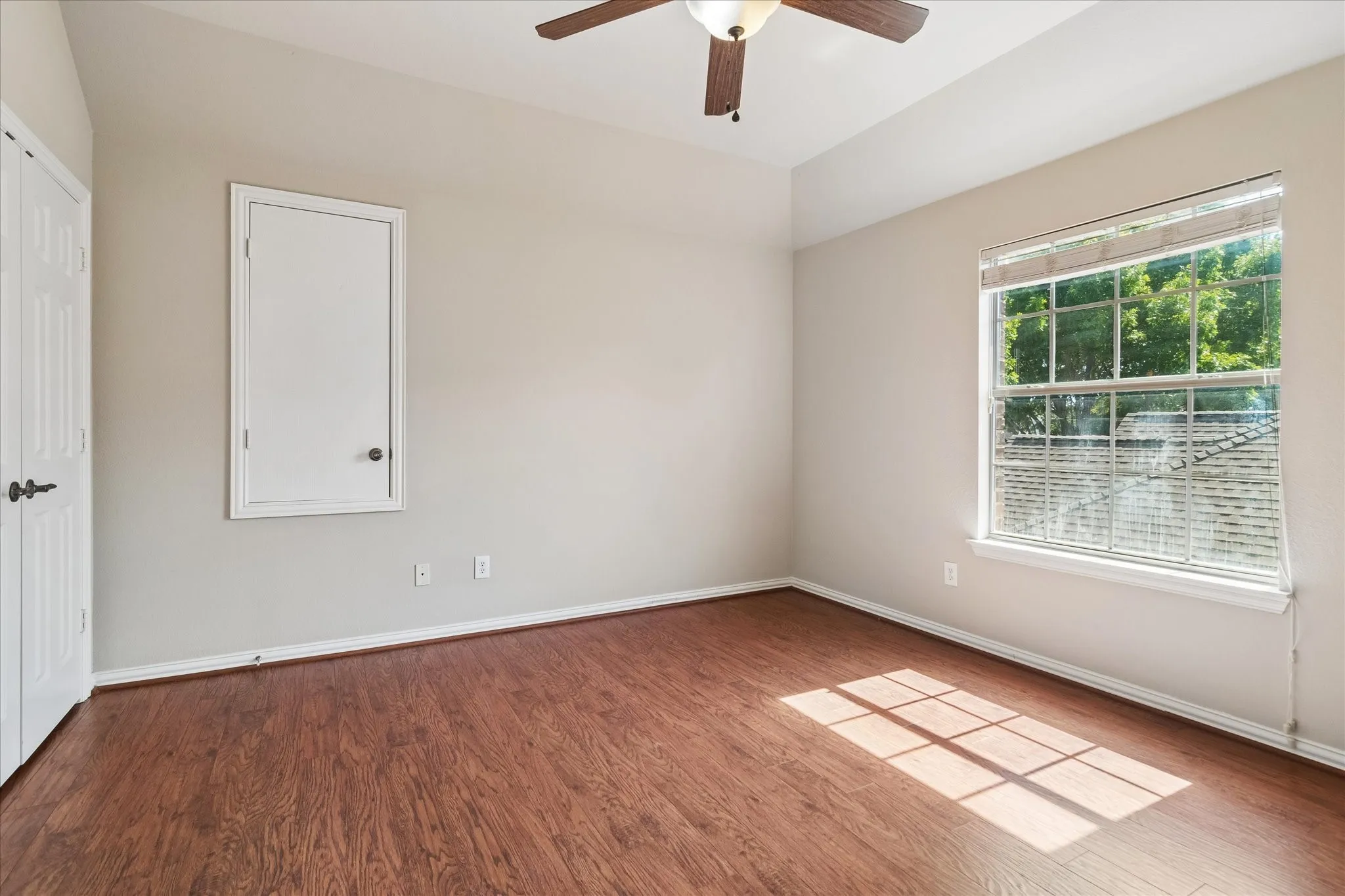 Room featuring wood-finish flooring, a ceiling fan, and a paneled door
