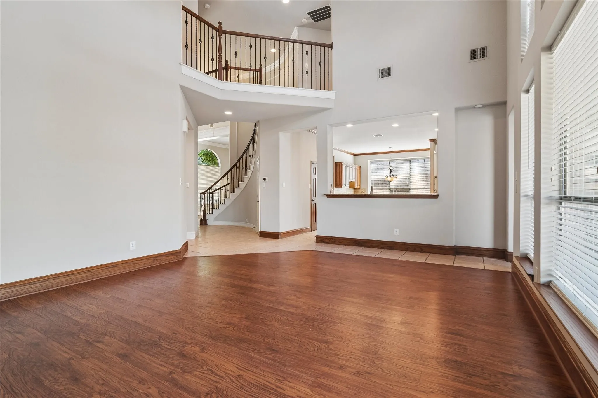 Expansive interior with wood-finish flooring, a spiral staircase, and an upper-level balcony