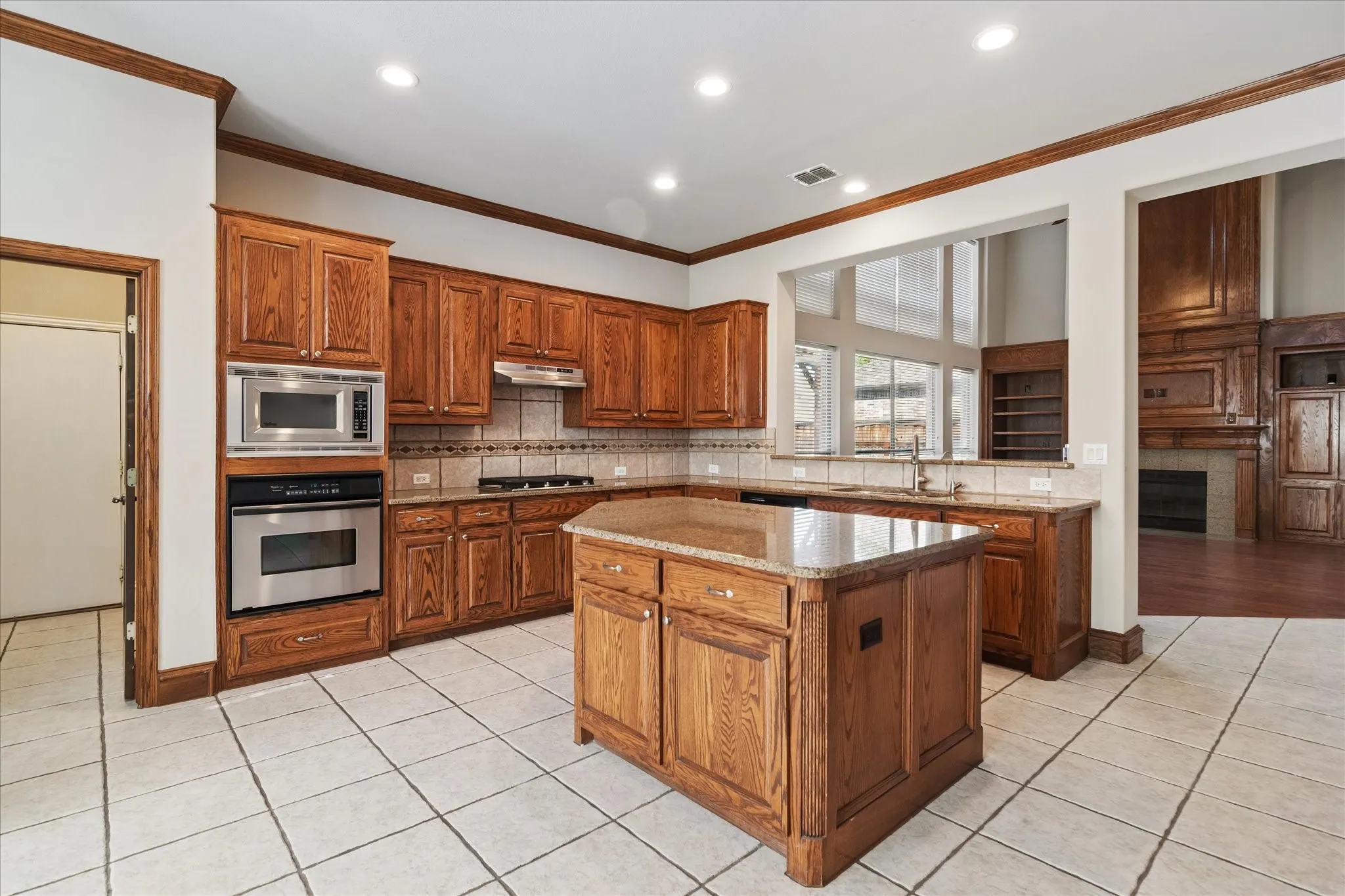 Kitchen featuring wood cabinetry, stainless steel appliances, a center island with a stone countertop, tile flooring, and recessed lighting