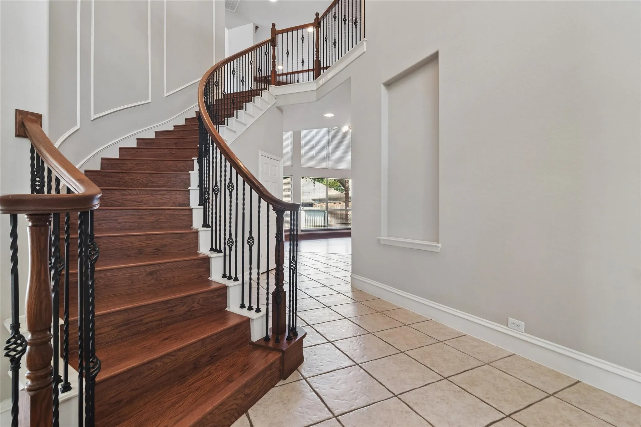 Curved staircase with wood-finish treads and wrought iron balusters