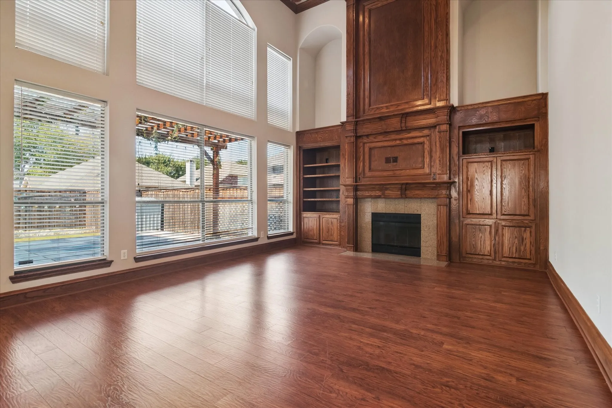 Expansive living space featuring wood-finish flooring, a full-height decorative wood mantel with built-in cabinetry, and a fireplace with a stone surround