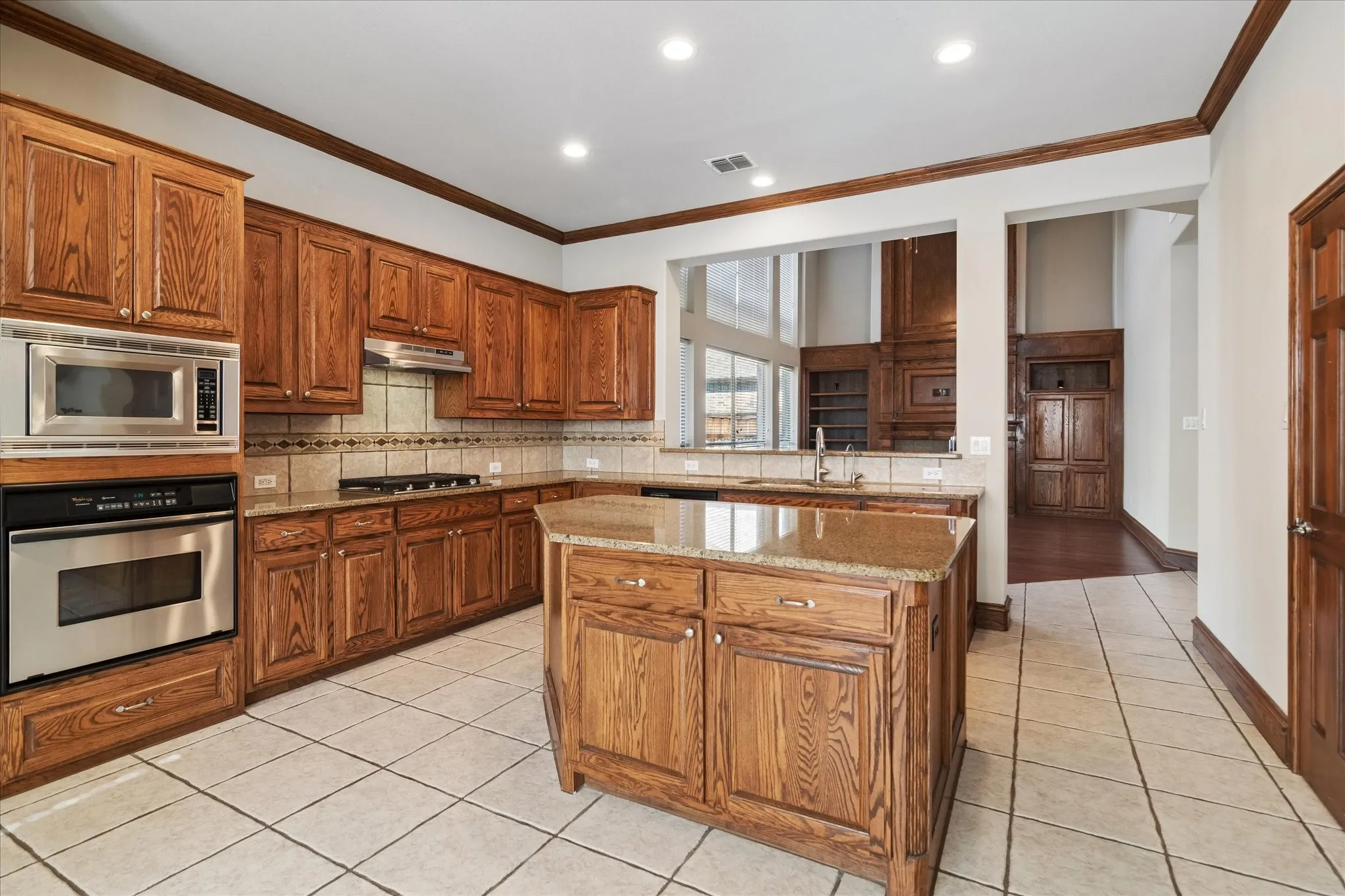 Kitchen featuring wood cabinetry, stainless steel appliances, a center island with a stone-finish countertop, and tile flooring