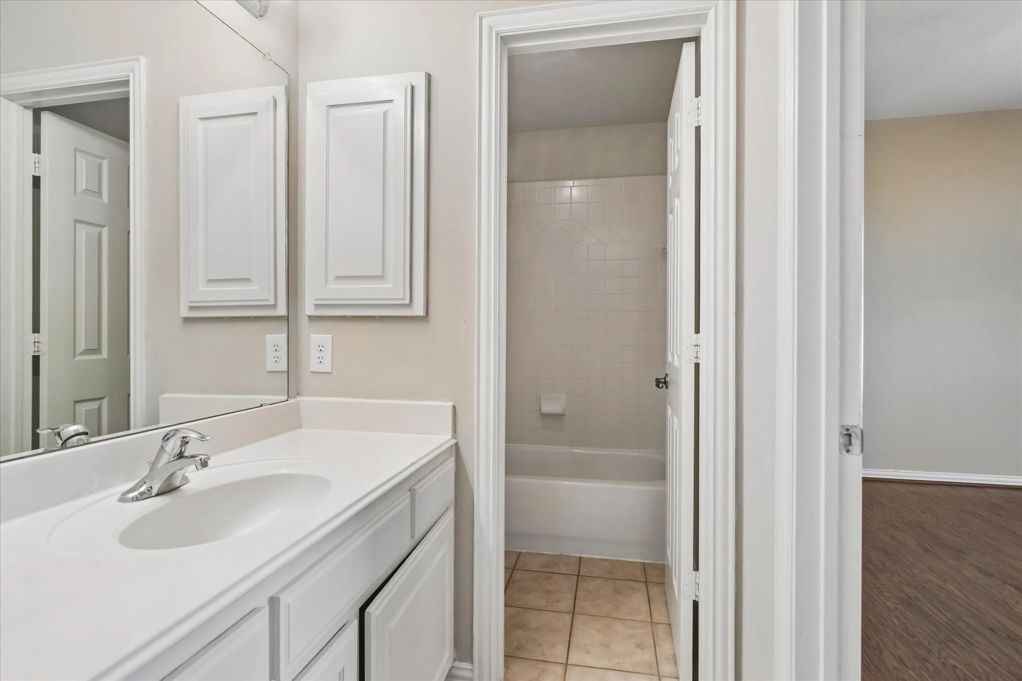 Bathroom vanity with integrated sink, chrome faucet, and white cabinetry
