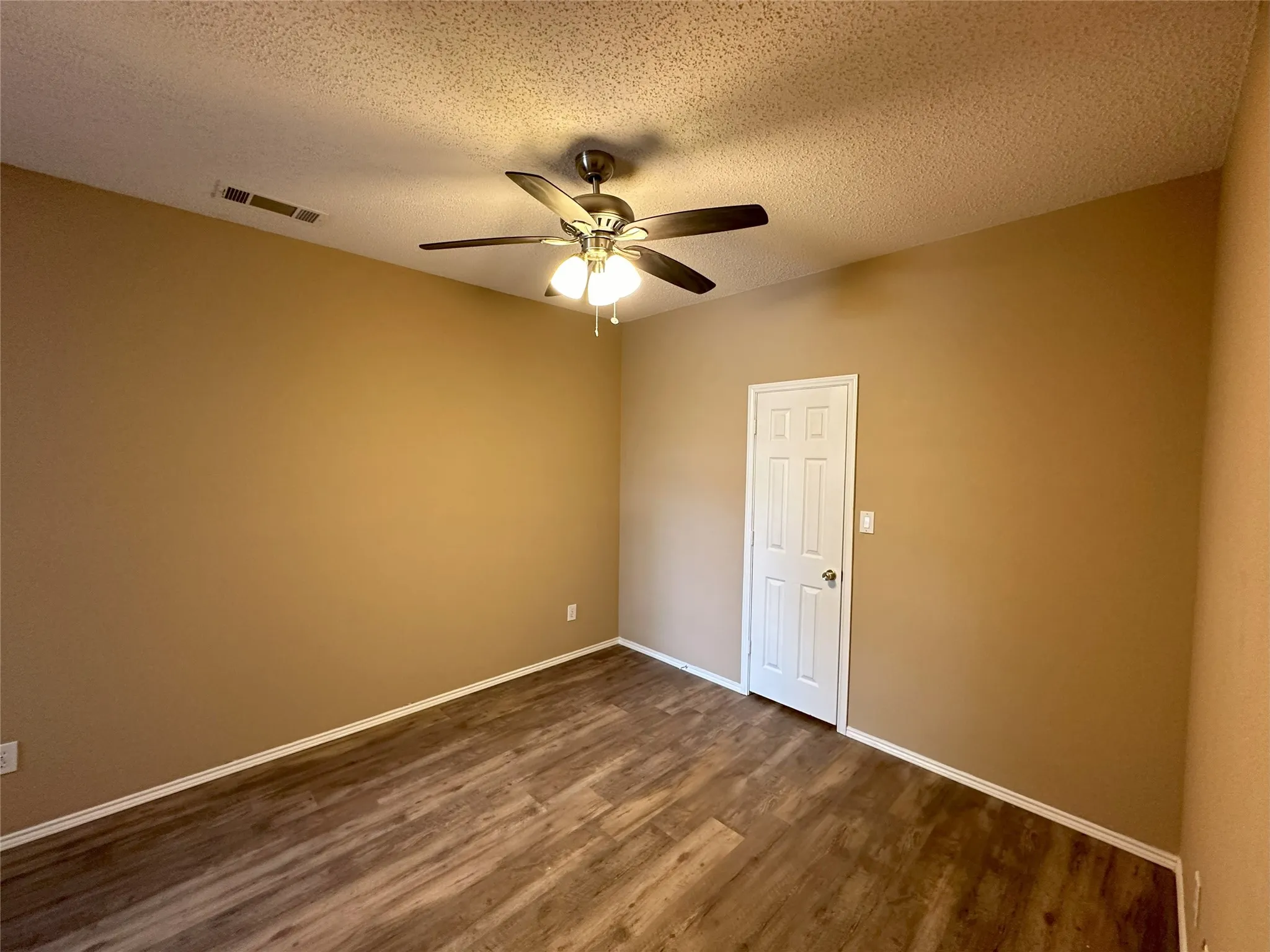 Wood-finish flooring with neutral wall tones and a white paneled door