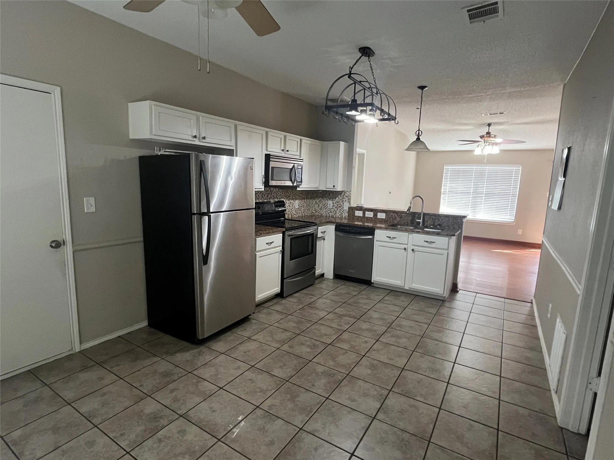 Kitchen featuring stainless steel appliances, white cabinetry, a double basin sink, and a tile backsplash