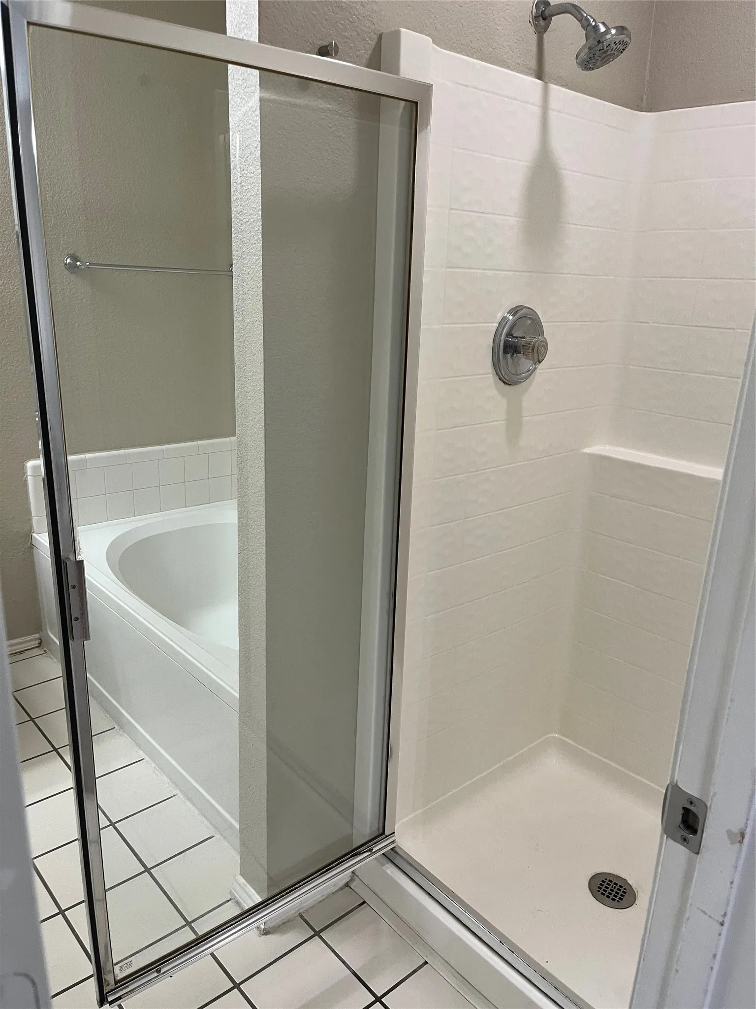 Shower enclosure with a glass door, white tiled walls, and a built-in shower shelf
