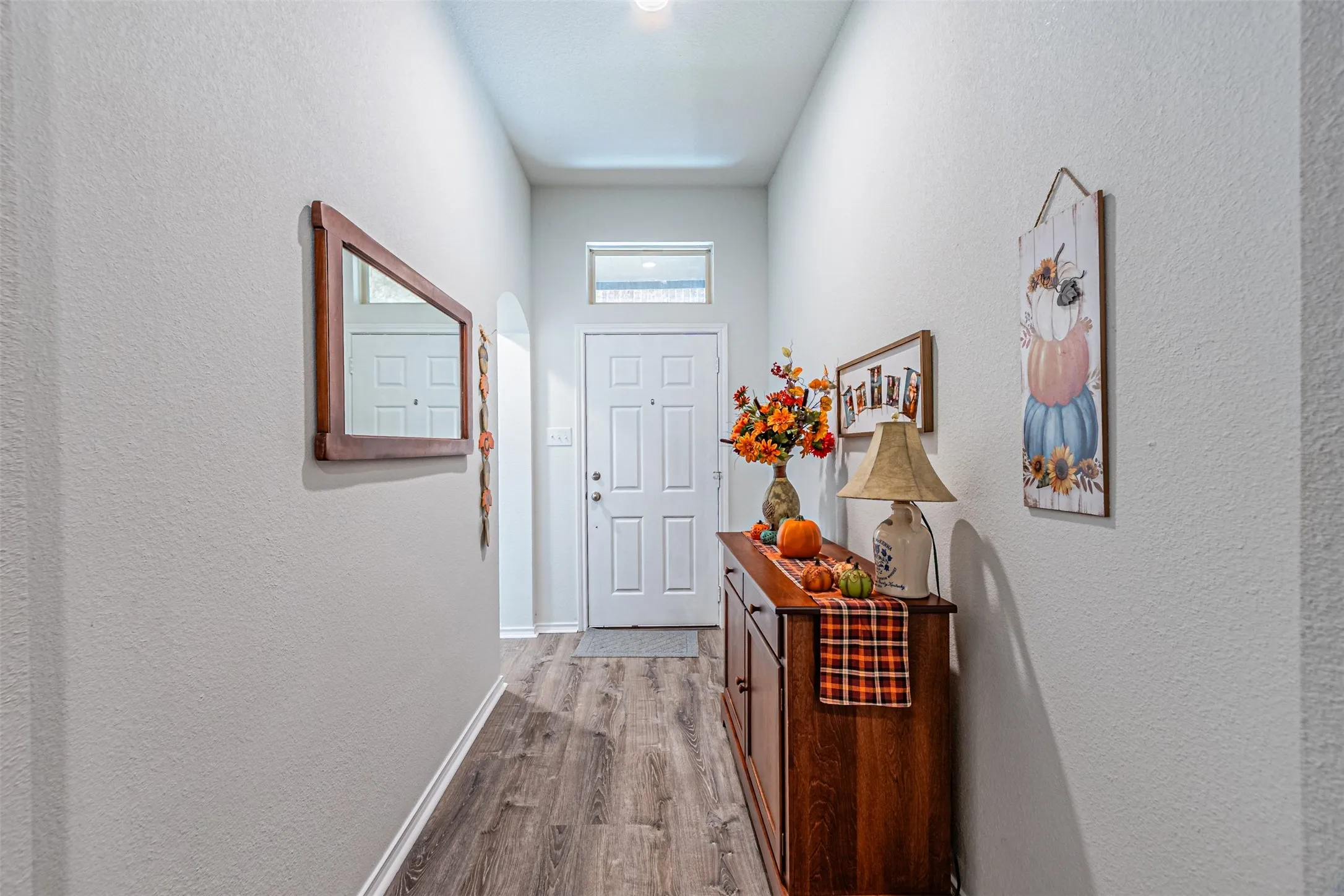 Recessed lighting, wood-finish flooring, white paneled door, arched doorway, and transom window