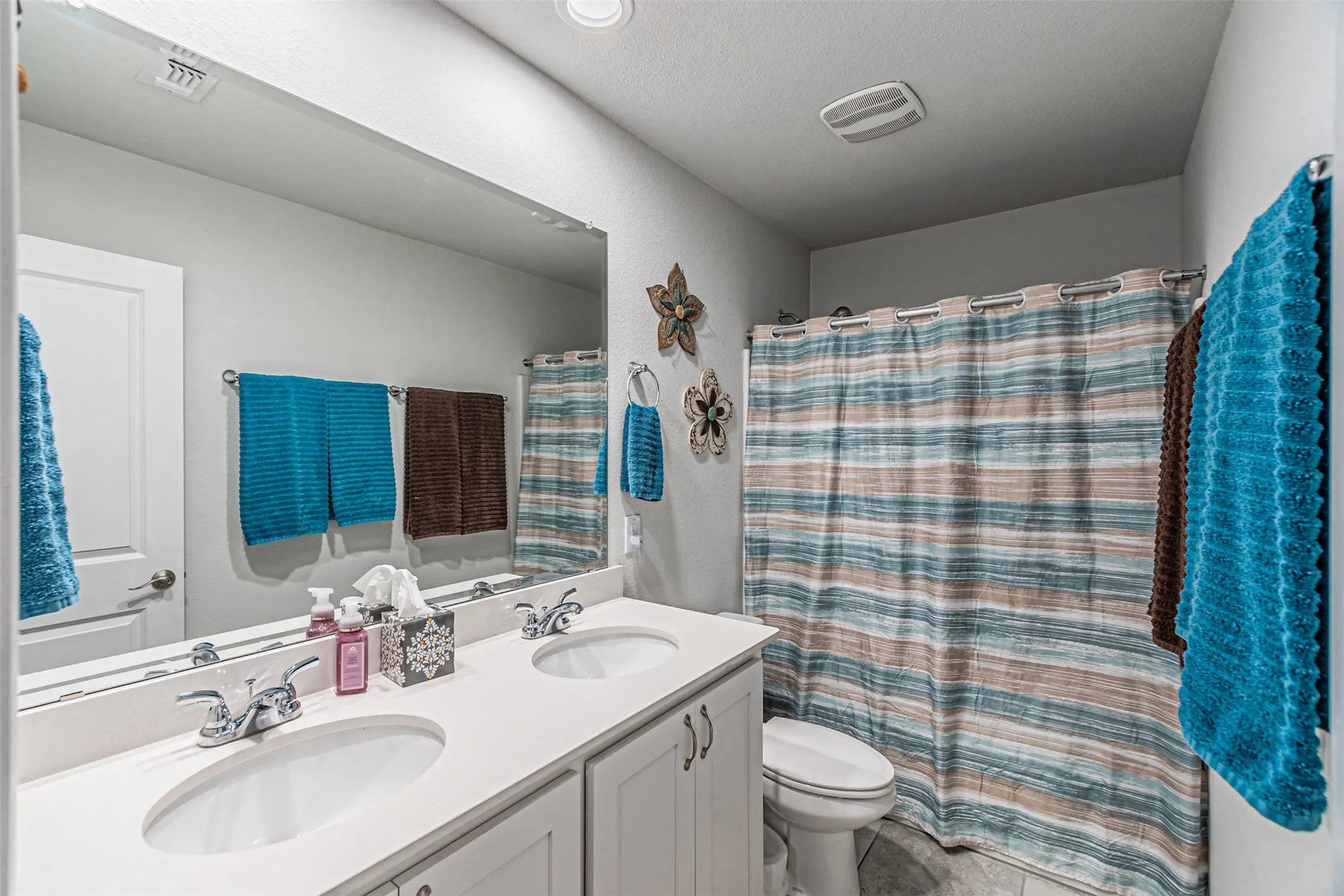 Dual vanity with integrated sinks, chrome fixtures, and white cabinetry