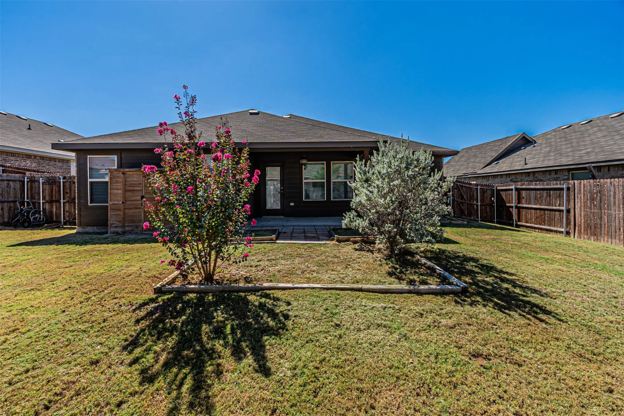 Expansive grassy backyard featuring a paved patio and mature landscaping