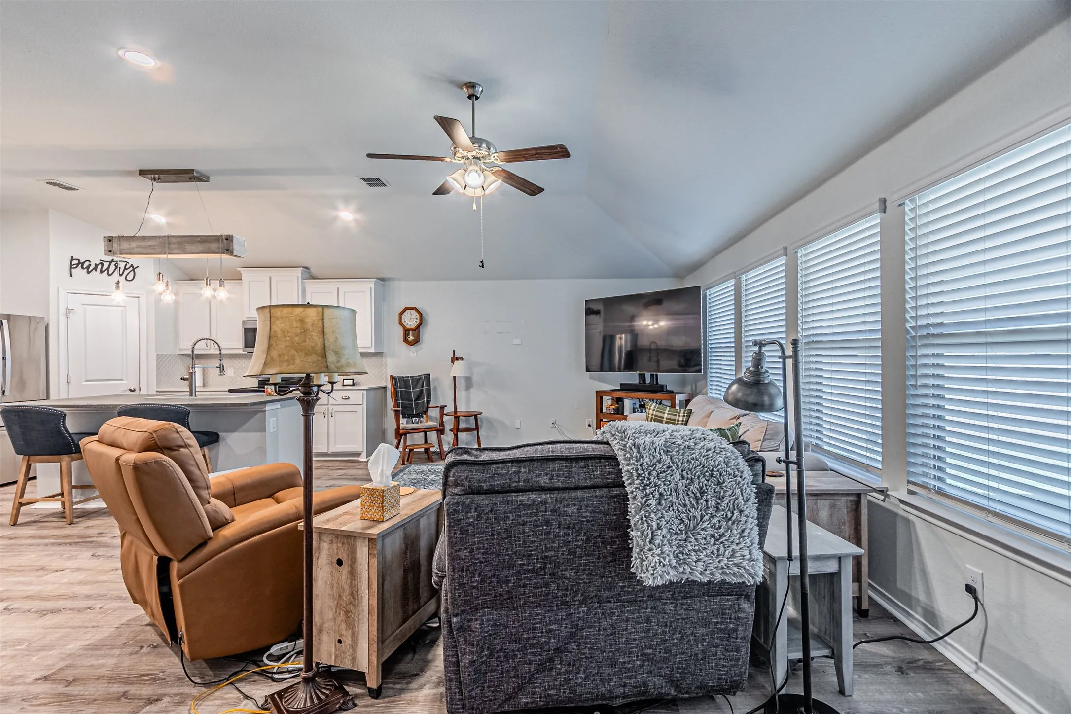 Vaulted ceilings, wood-finish flooring, recessed lighting, and a ceiling fan