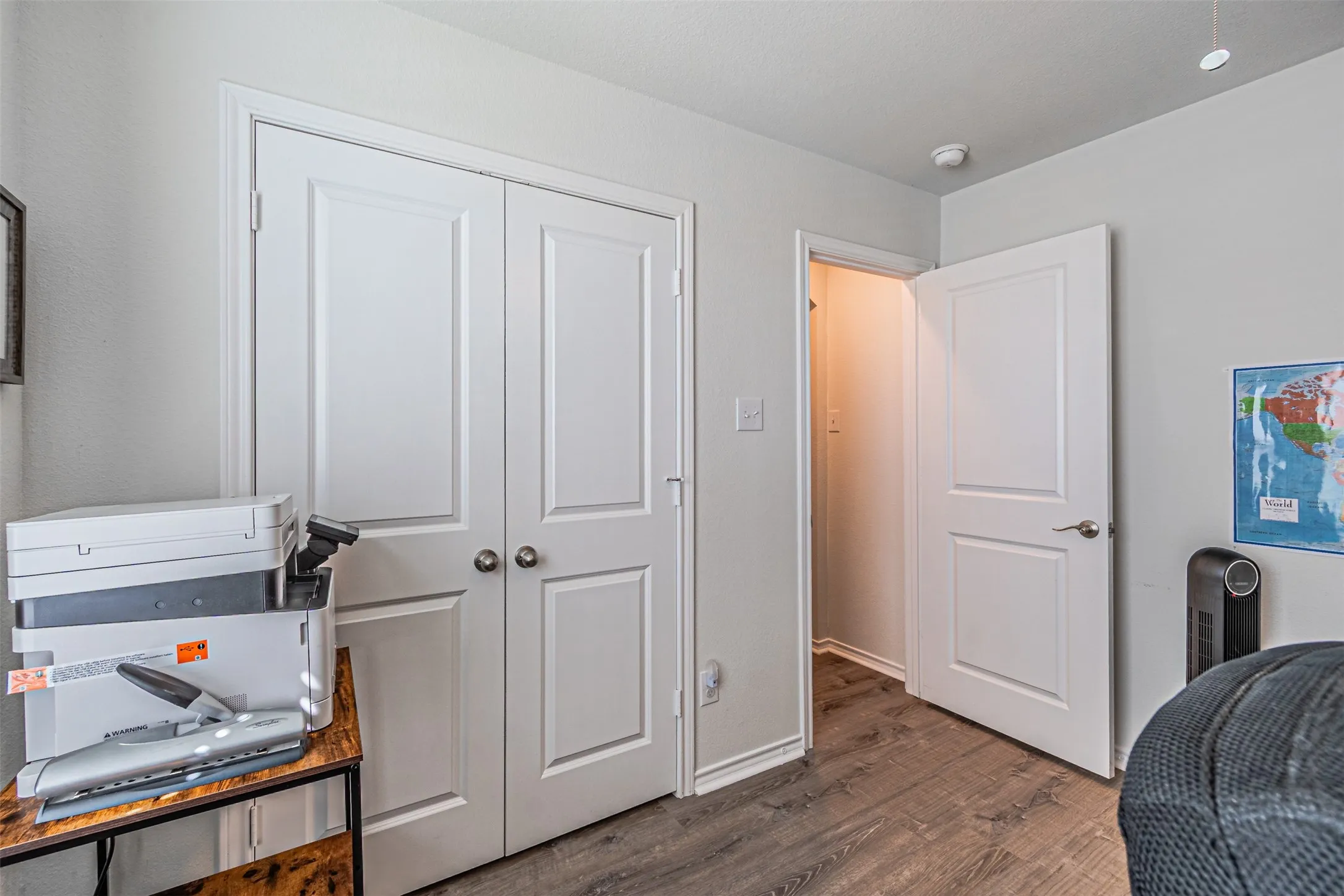Wood-finish flooring with white trim, two-panel interior doors, and a double-door closet