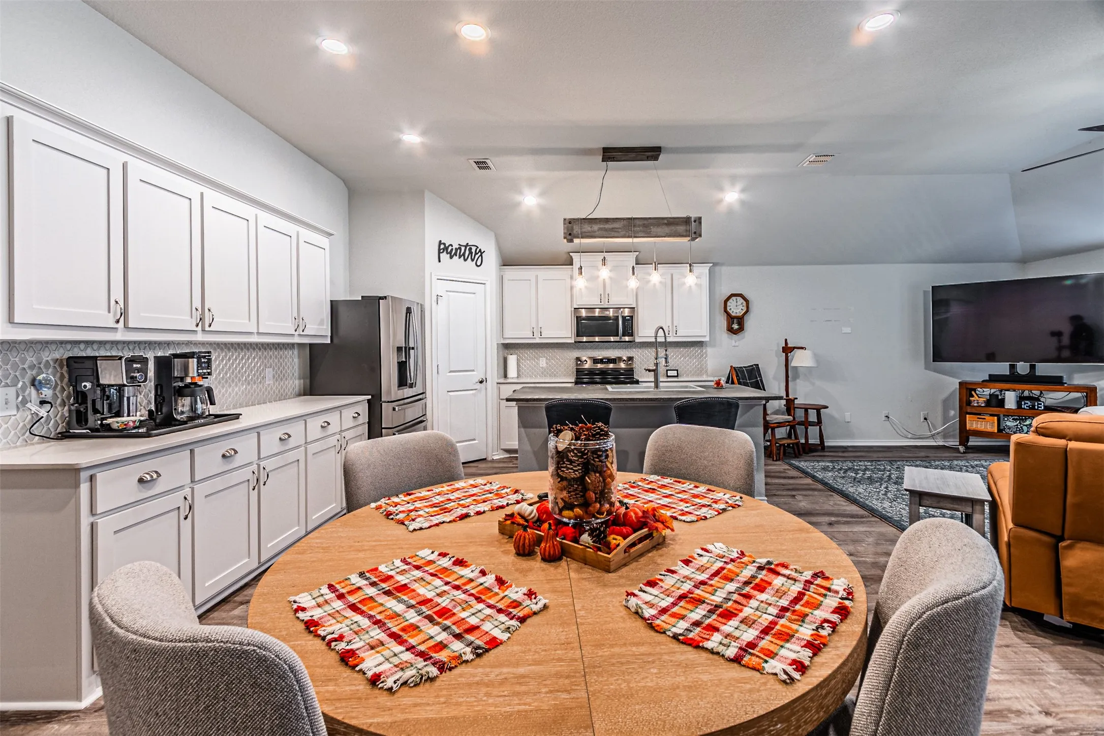 Kitchen and dining area featuring white cabinetry, gray countertops, a mosaic tile backsplash, and stainless steel appliances