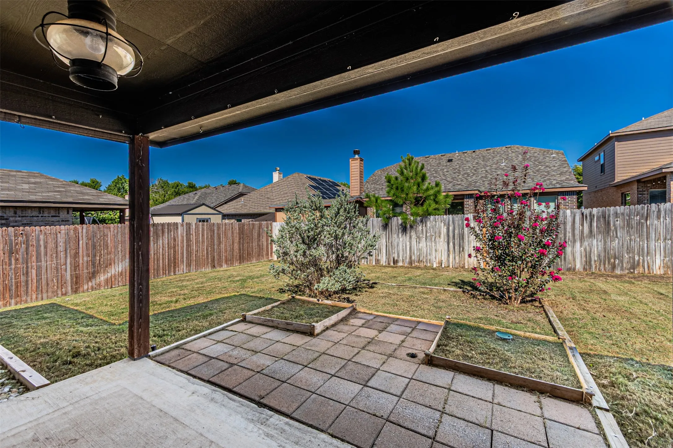 Covered patio featuring an attached overhead light fixture, concrete flooring, and a paver patio area