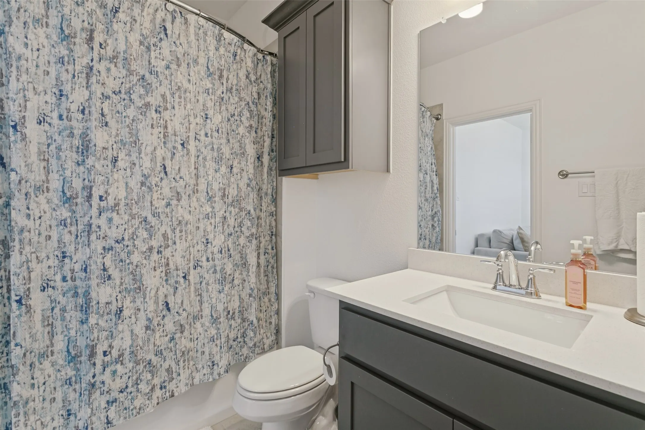 Bathroom featuring a single vanity with dark cabinetry, integrated sink, and a framed mirror