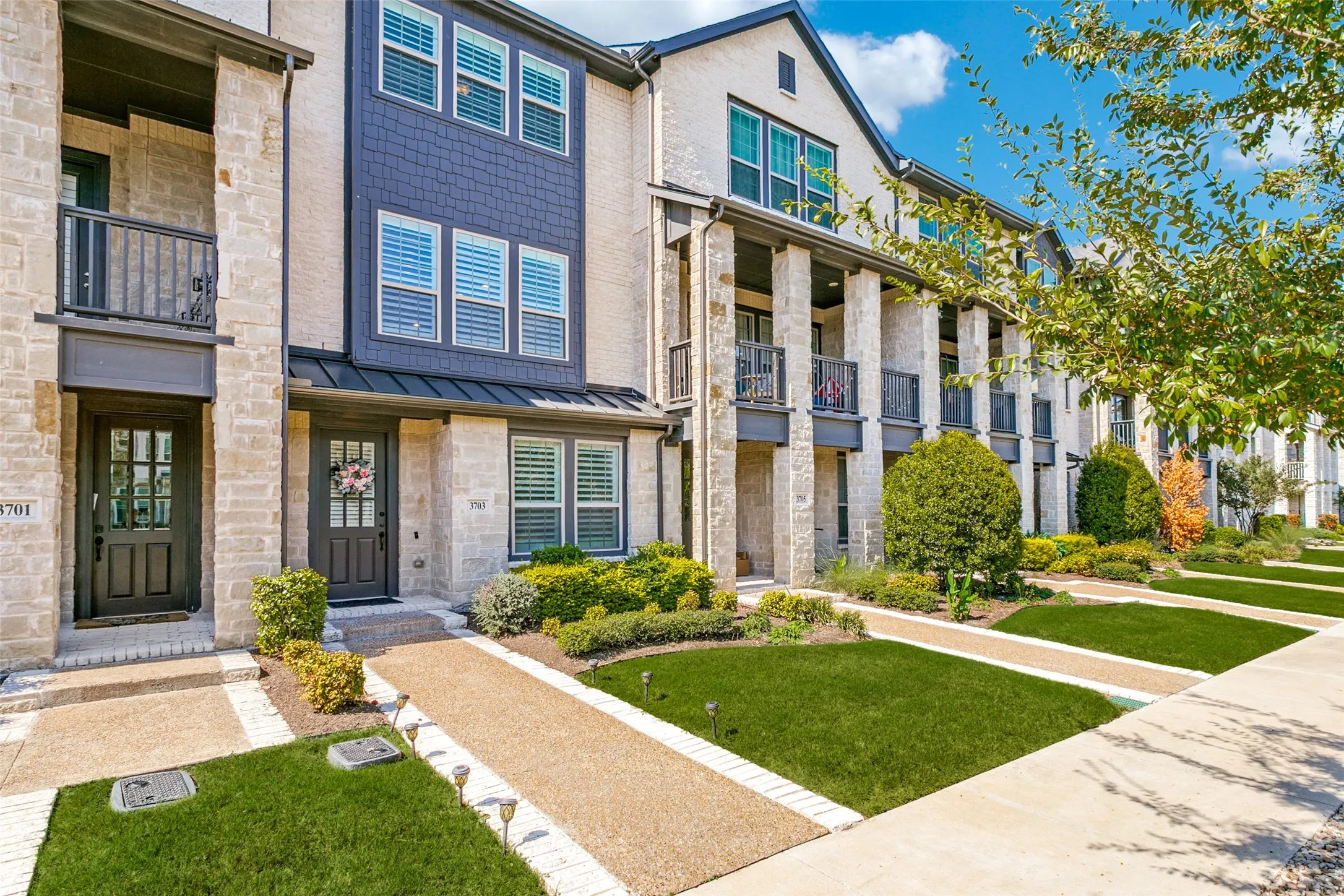 Stucco exterior with stone accents, dark entry door, and ground-level landscaping