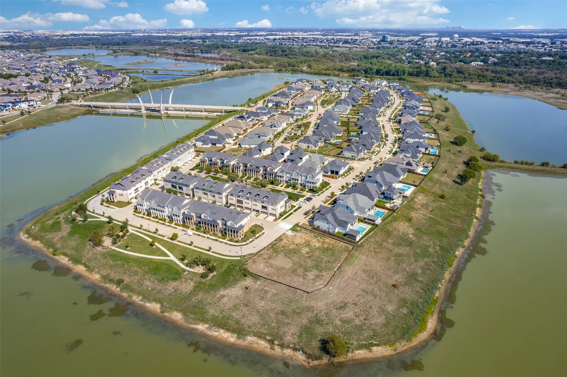 Waterfront community featuring single-family residences and townhomes, a modern architectural bridge, and individual swimming pools