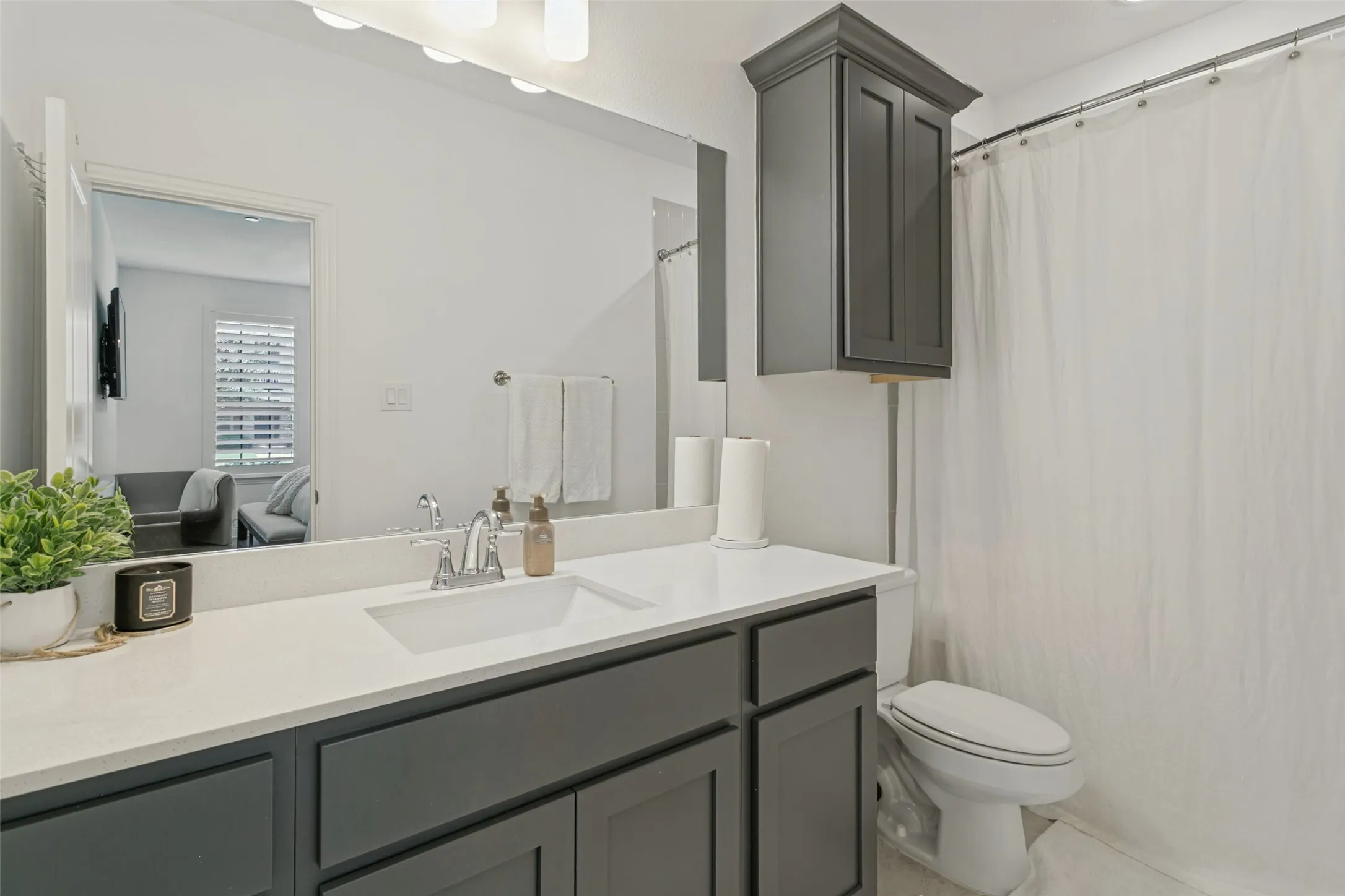 Vanity with a white countertop and integrated sink, chrome faucet, and gray cabinetry