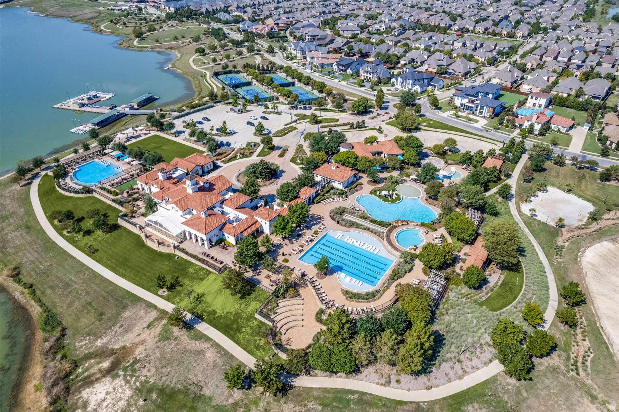 Expansive community with multiple swimming pools, sports courts, and a club house building