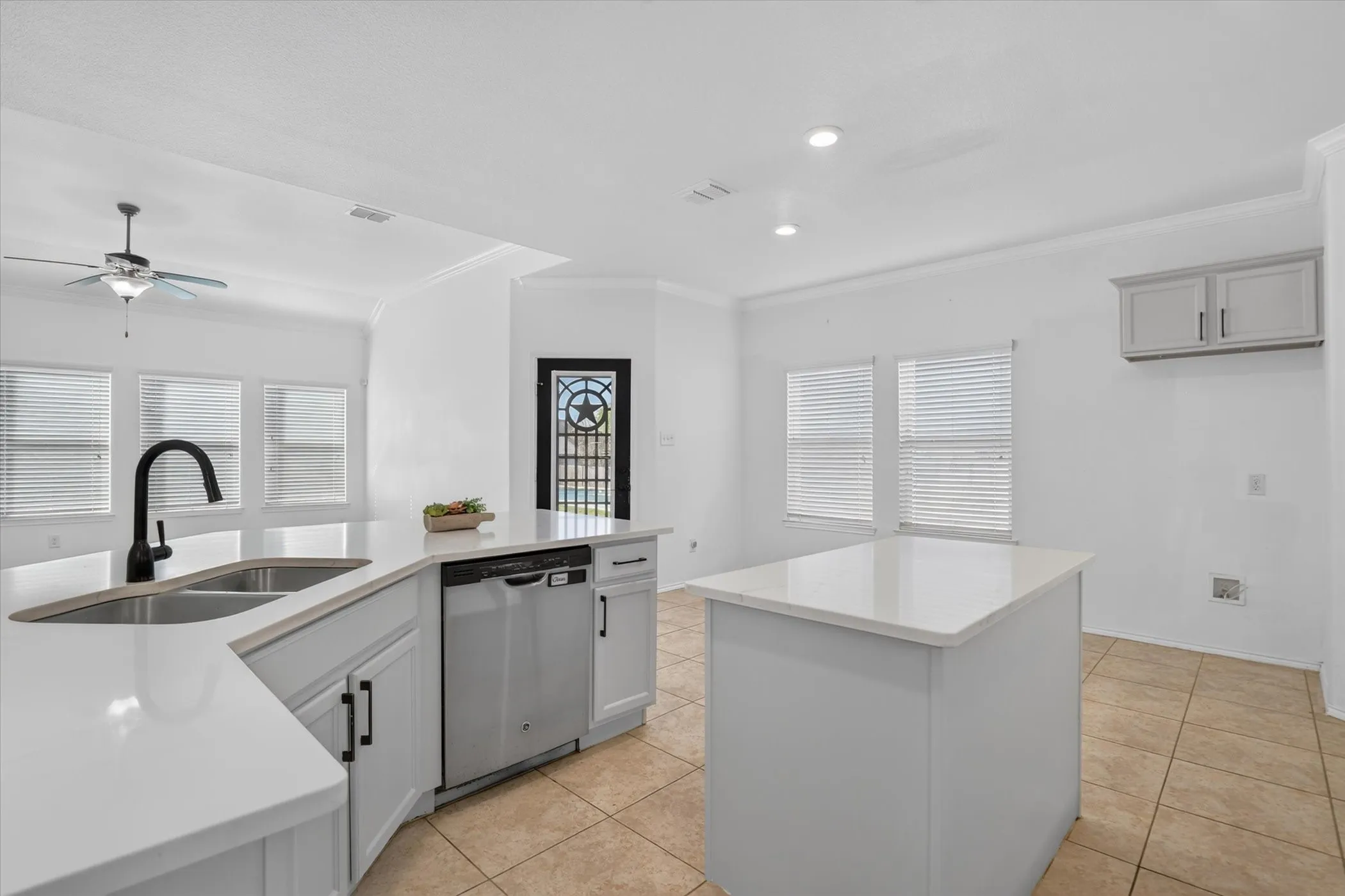 Kitchen featuring white cabinetry, stainless steel appliances, a double basin sink with a matte black faucet, and a center island