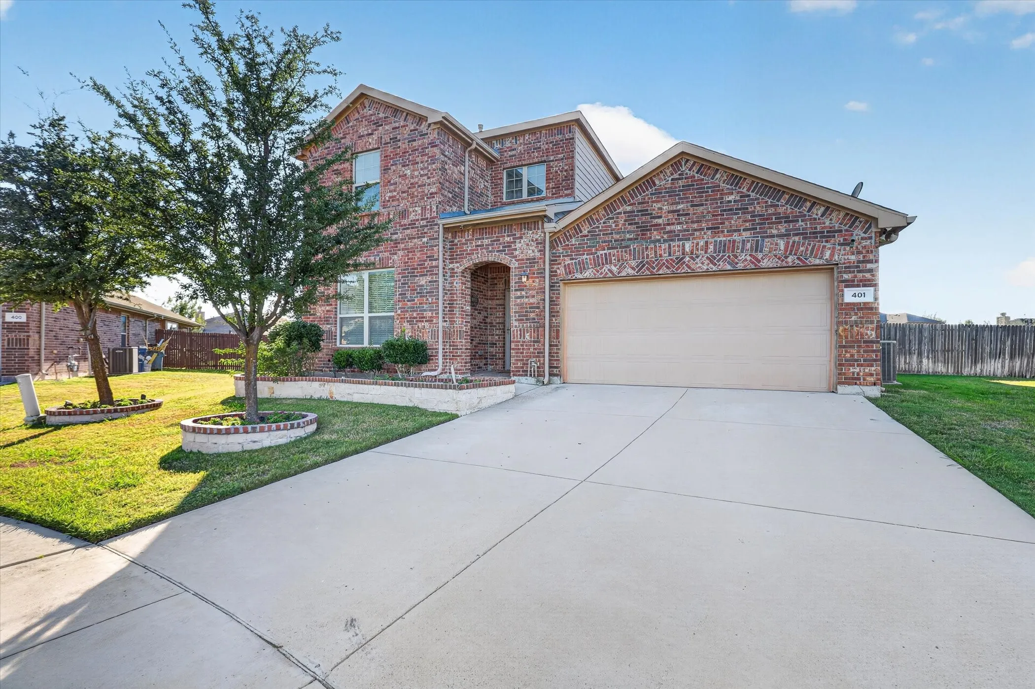 Two-story brick exterior with an arched entryway, attached garage, concrete driveway, and landscaped front yard
