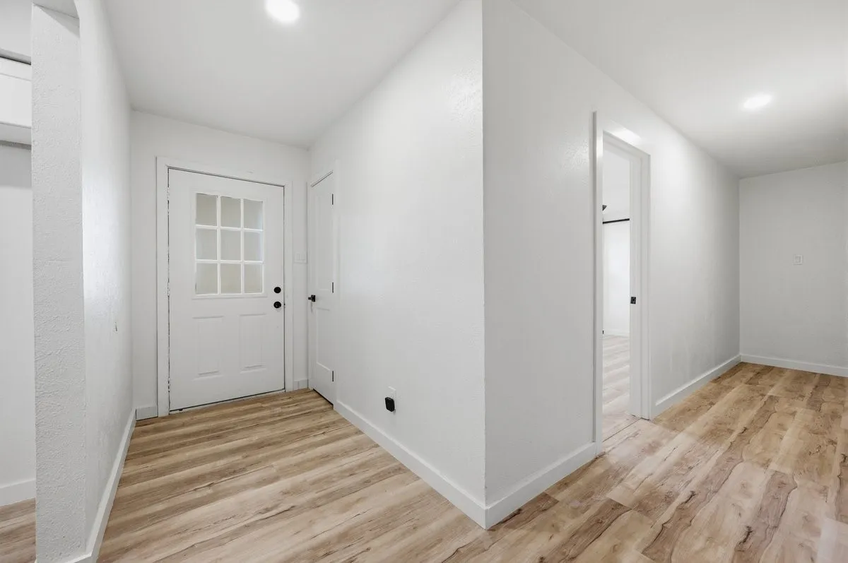 View from living room to front door with bedroom hallway to the right
