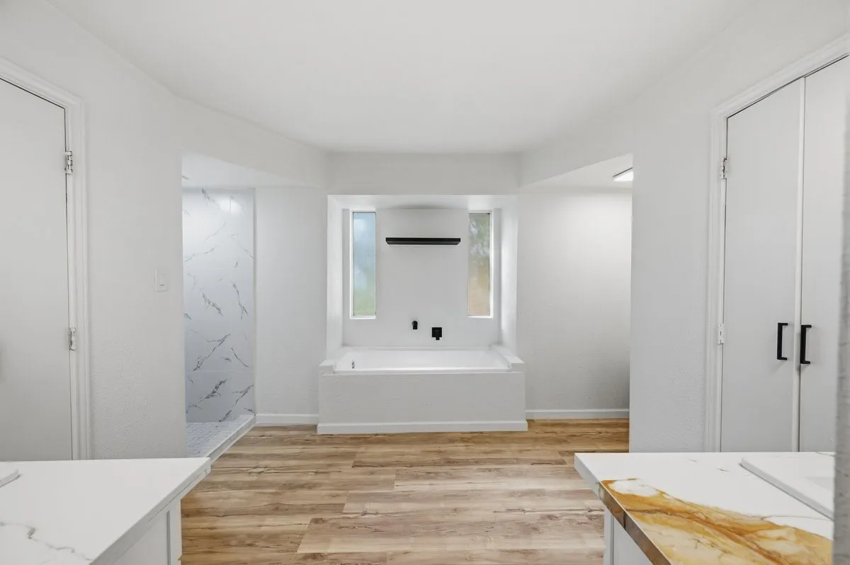 Gorgeous primary bathroom with deep soaking tub, walk-in shower, quartz countertops, and his & her walk-in closets!