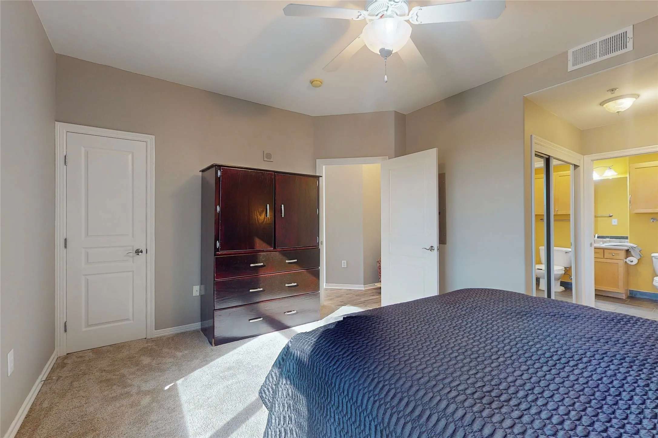 Bedroom with light carpet, connected bathroom, and ceiling fan