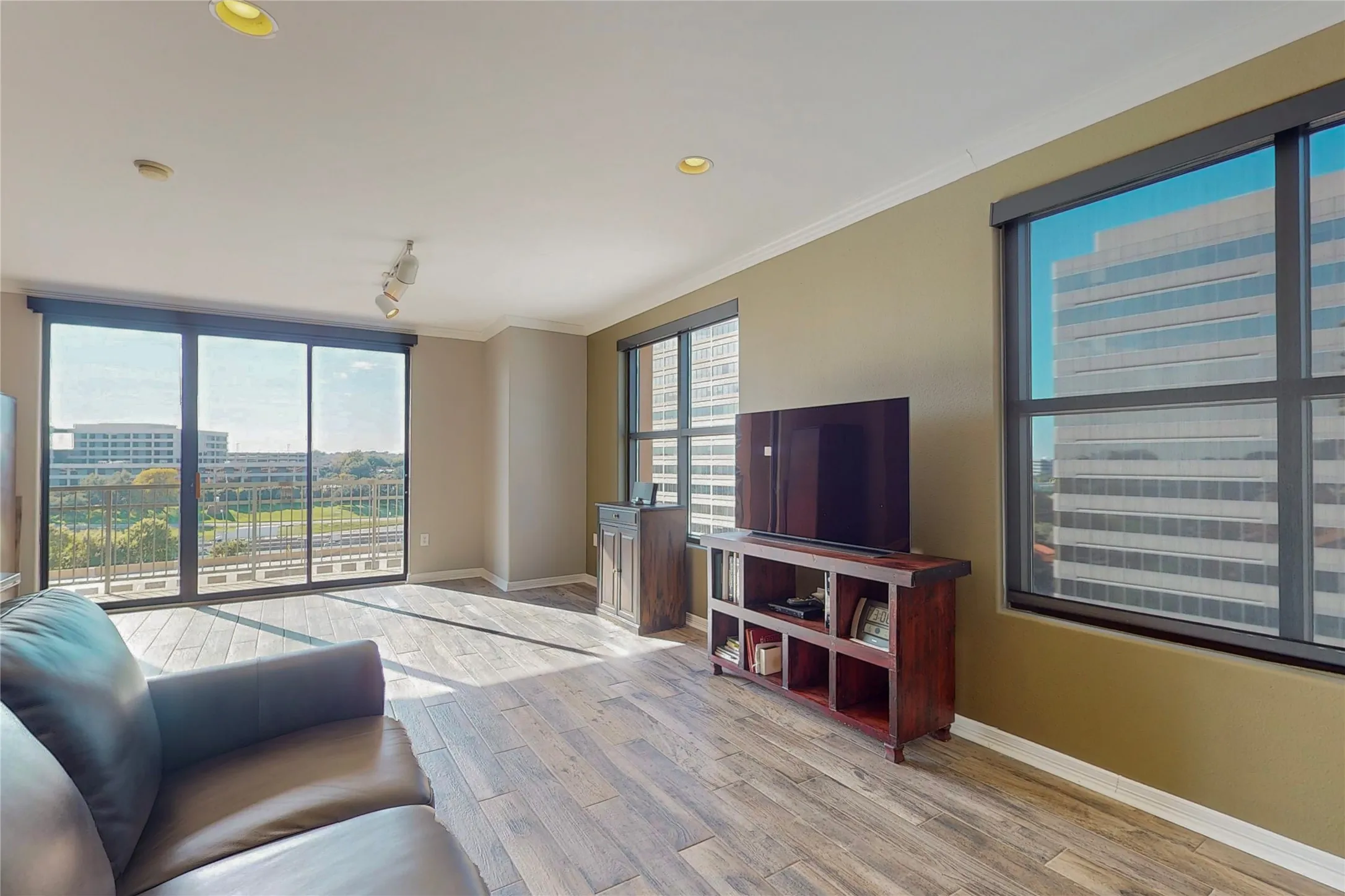 Living room featuring ornamental molding, rail lighting, a healthy amount of sunlight, and light hardwood / wood-style floors