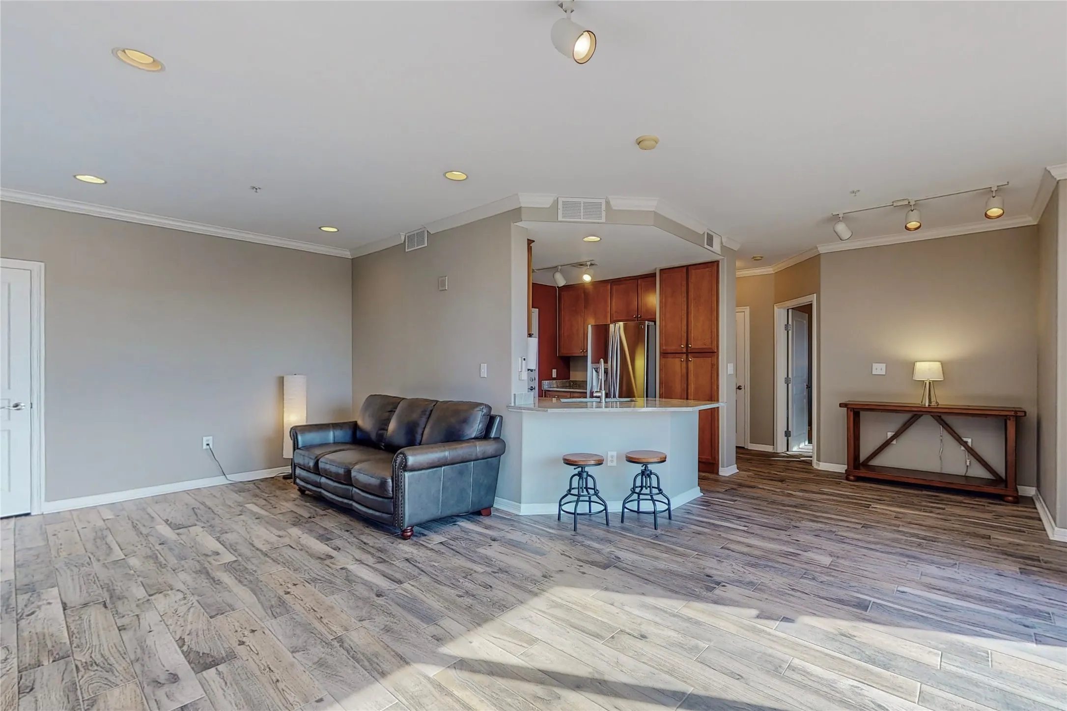 Living room with crown molding, track lighting, and light wood-type flooring